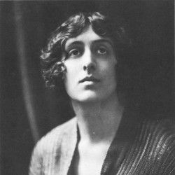 A black and white photograph of Vita Sackville-West, a white woman with angular features and short, curled hair parted in the middle and pushed back. She wears a knit top.