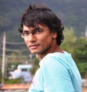 Xulhaz Mannan, a Bangladeshi man with light brown skin and wavy dark brown hair. He wears frameless glasses and a light blue T-shirt.