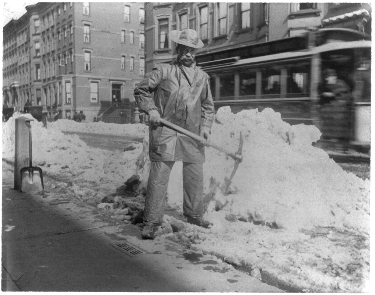 Street types of New York City: Street cleaner with pick ax standing in front of pile of snow 