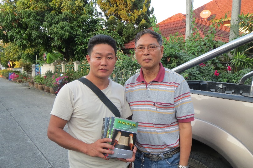 Ahpu and a student distributing several copies of Ahpu's book.