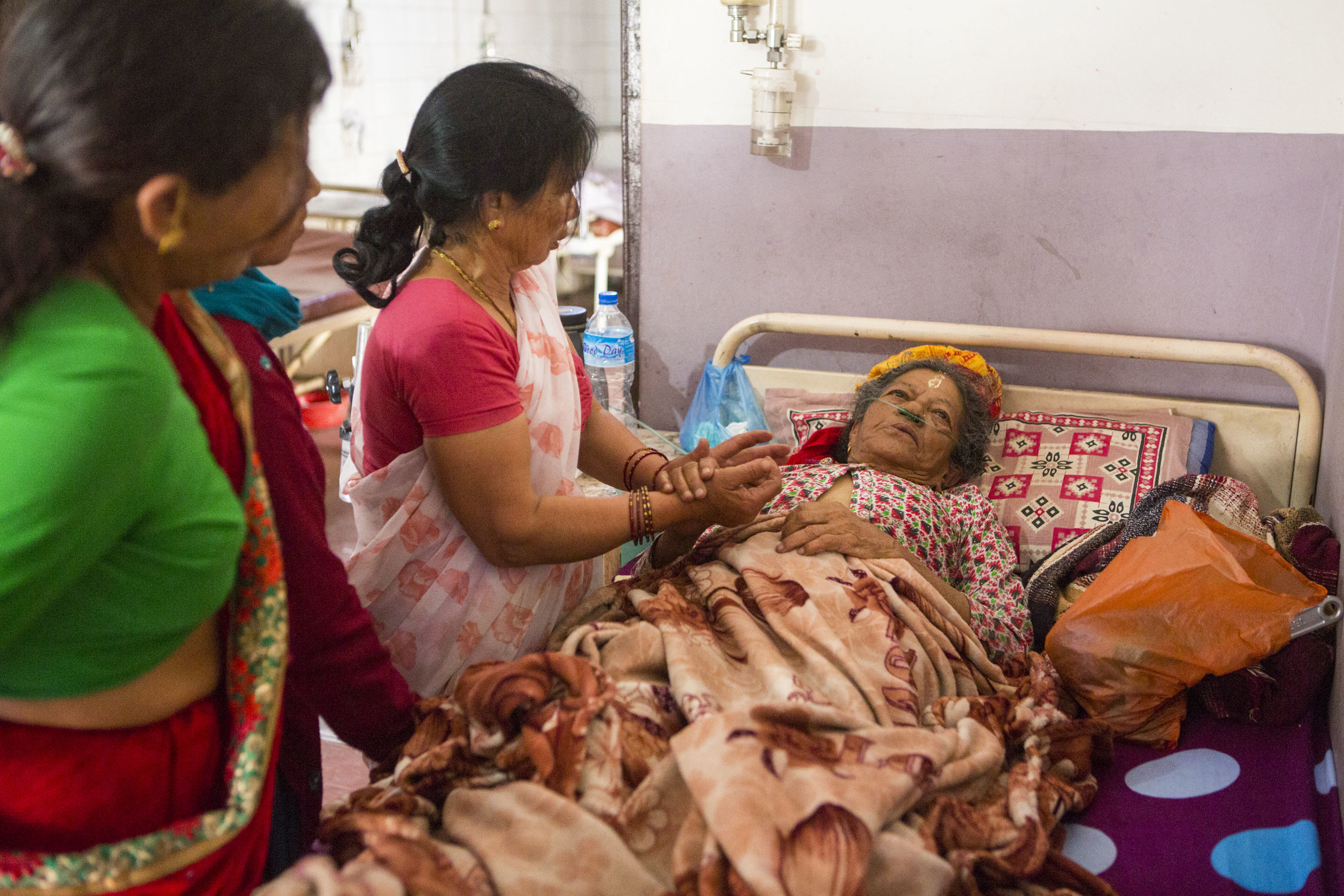  Family members stand by Suvandra Parajule's side as she lay dying at Pashupati's hospice care on May 15, 2016, in Kathmandu, Nepal. The family brought Parajule there to start the traditional cremation process immediately after her death. 