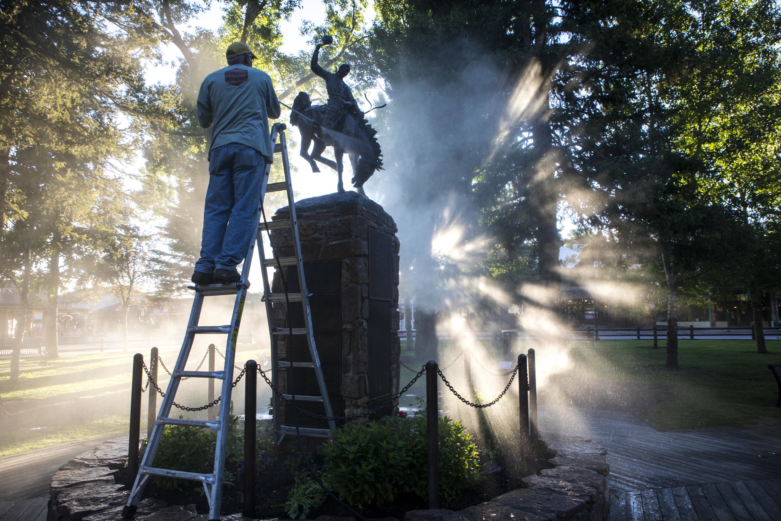  David DeDecker power washes the bucking bronco on top of the Town Square Veterans Monument as the early morning sun peeked through the trees on June 24, 2018 in Jackson, Wyo. The monument honors area service personnel from World War I to Operation D