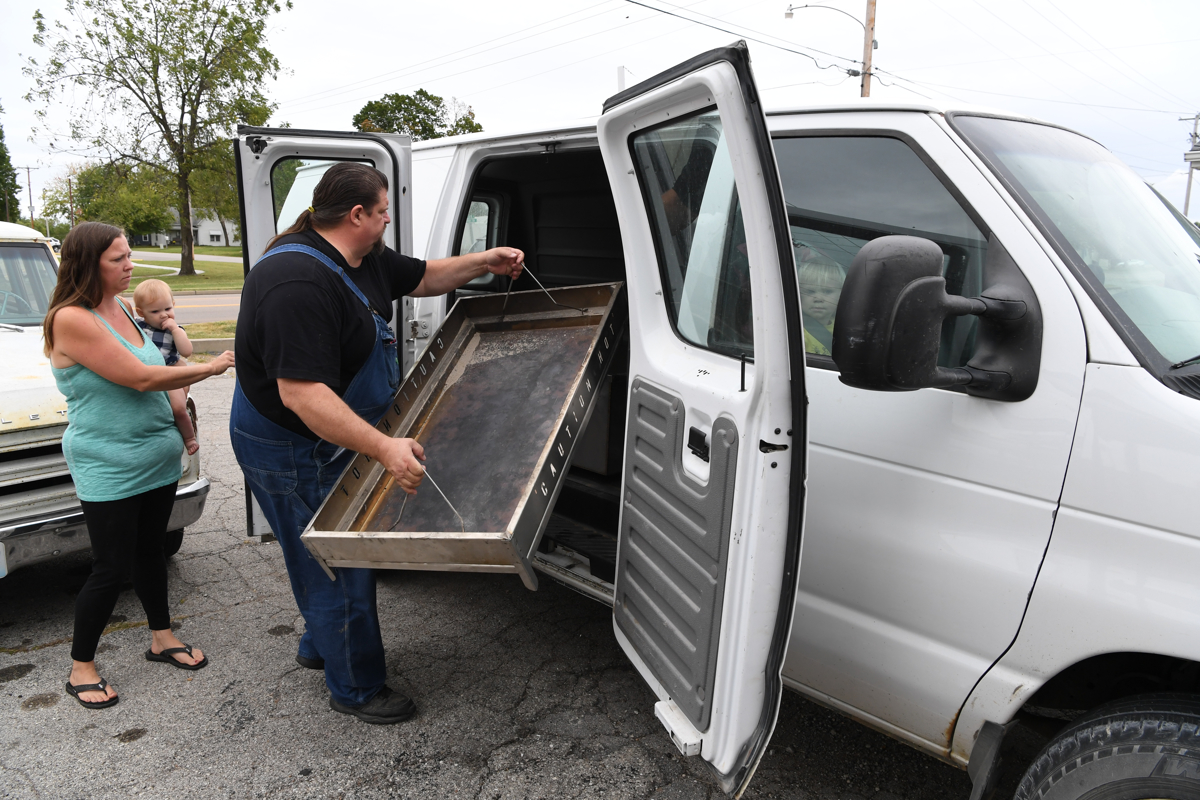  Blake loads a roaster into his van as his girlfriend Courtney See and their daughter Presley watch. 