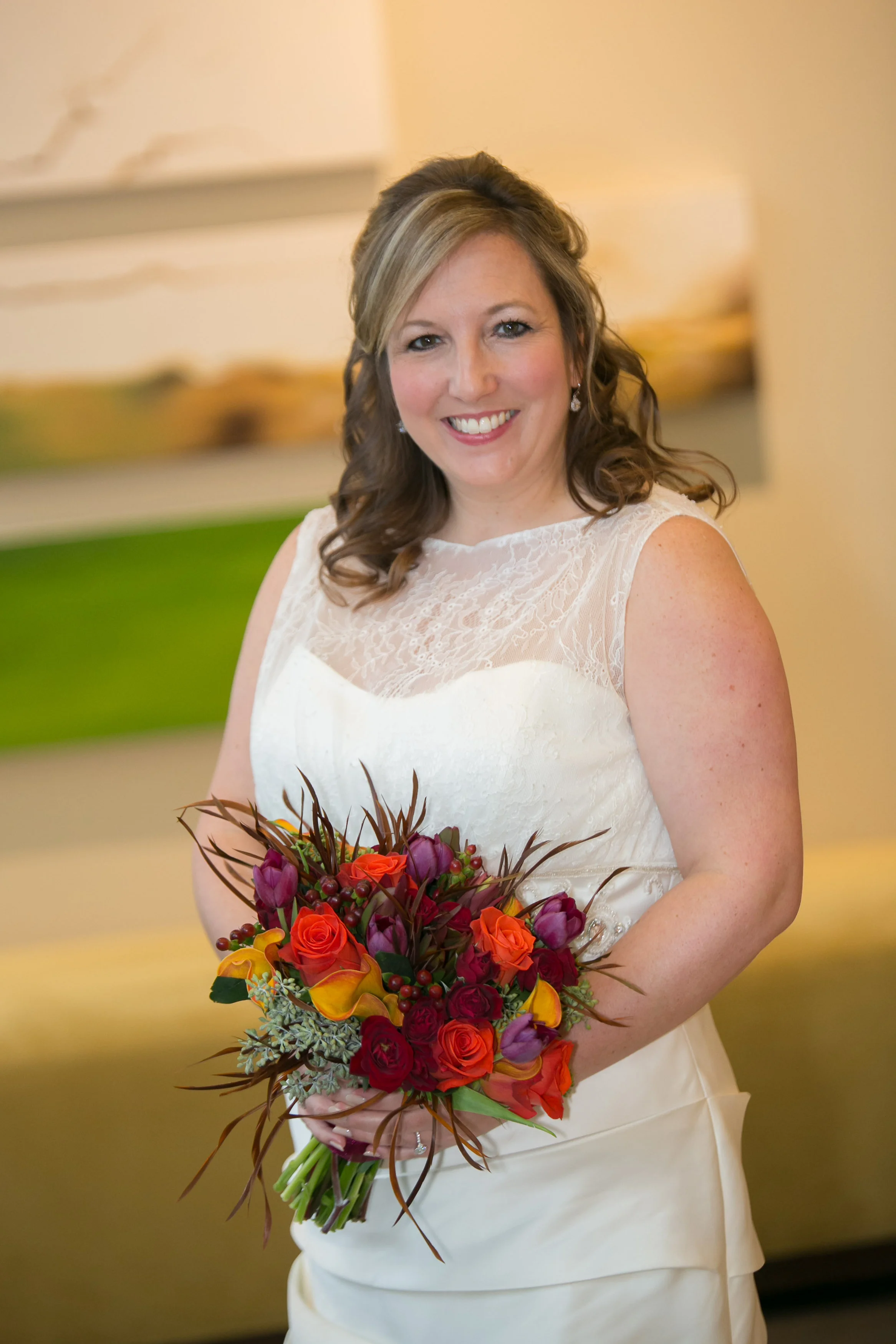 Amy chose a bright mix of fall colors for her and her daughter's bouquets. The rich orange roses were accented with purple tupils, yellow calla lilies, deep red spray roses, burgundy hypericum berry. The seeded eucalyptus,sunset leucadendron and feathers completed this impactful mix of flowers.