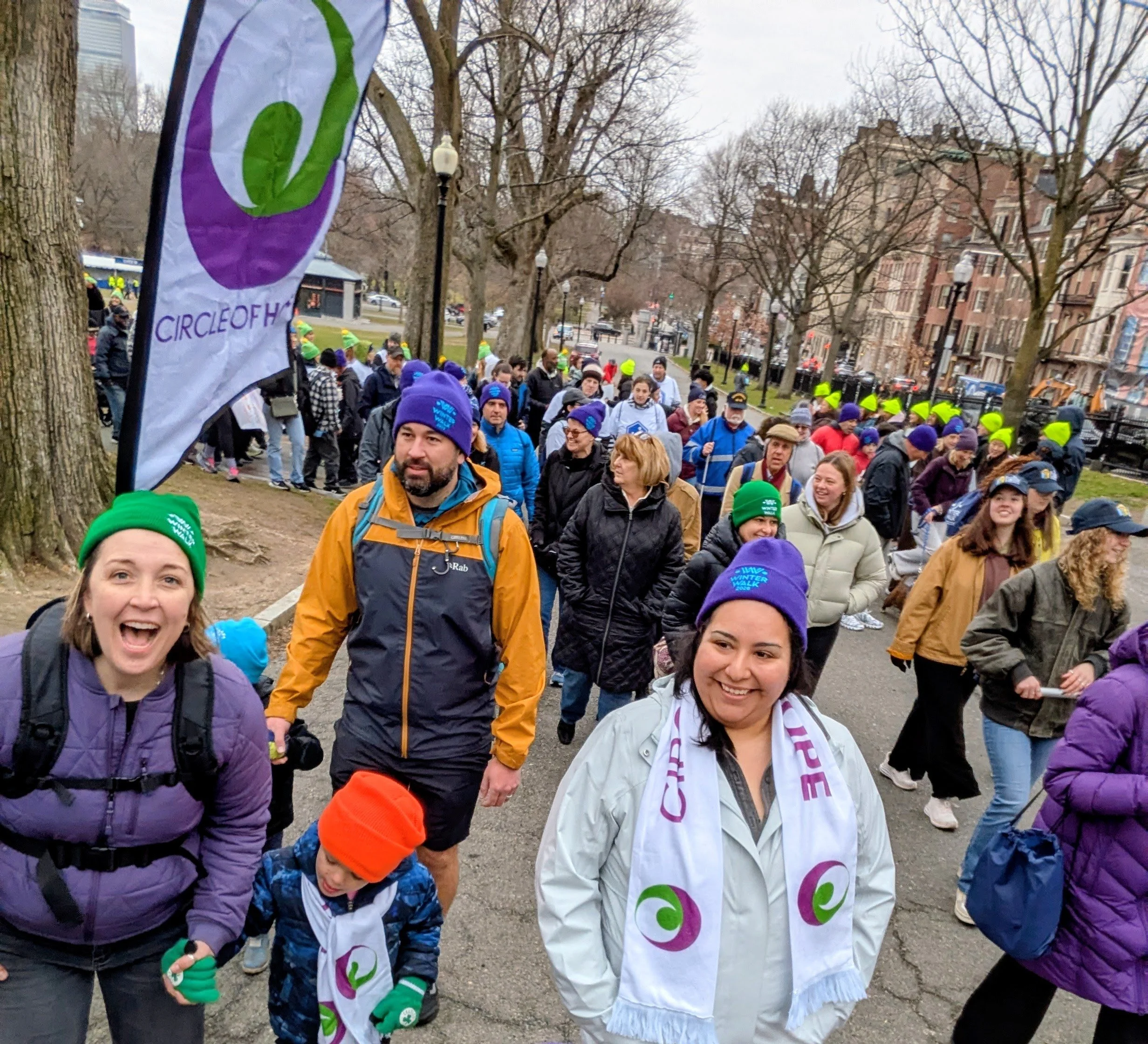 Hundreds of people are pictured walking on Boston Common for the 2026 Winter Walk. Members of the Circle of Hope team are in the foreground with a Circle of Hope backpack flag.