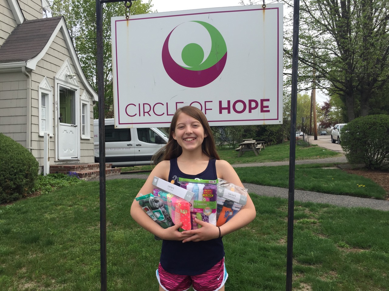 A young donor stands with donations in front of Circle of Hope sign
