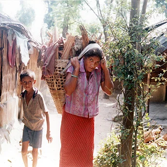 A woman with a bundle of firewood on her back is selling it in the refugee camps. Refugees are not allowed to fetch firewood from the forest so they have to buy it- the brickettes provided are not sufficient for cooking. Til Maya / PhotoVoice / LWF