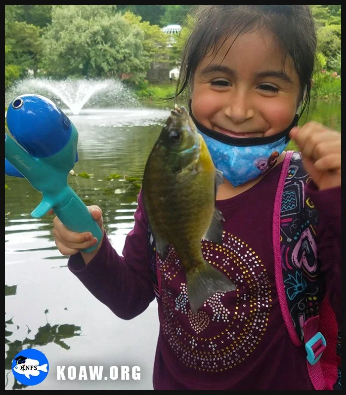 Young girl with fish caught using a spincast, or button-push, reel.