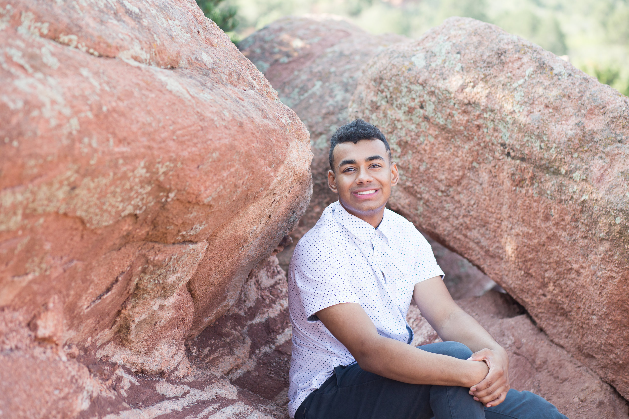 Liberty High School senior boy sitting around red rocks in  Garden of the Gods for photos Stacy Carosa Photography