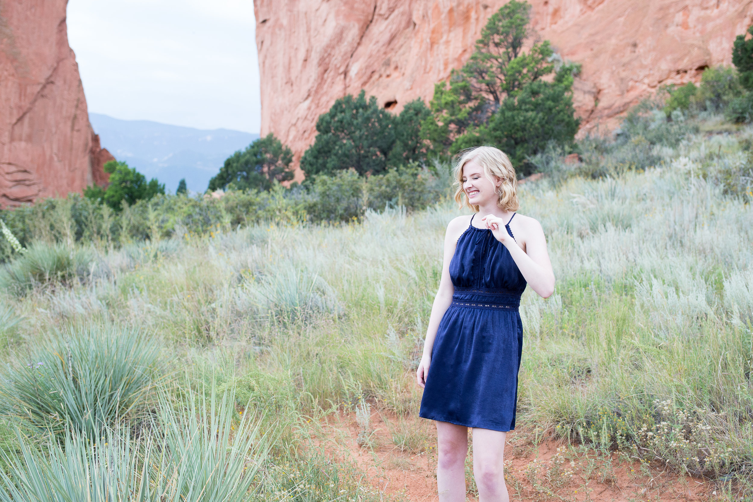 Girl laughing and looking in the distance with Garden of the Gods in the background for her senior photo shoot, Stacy Carosa Photography, Colorado Springs