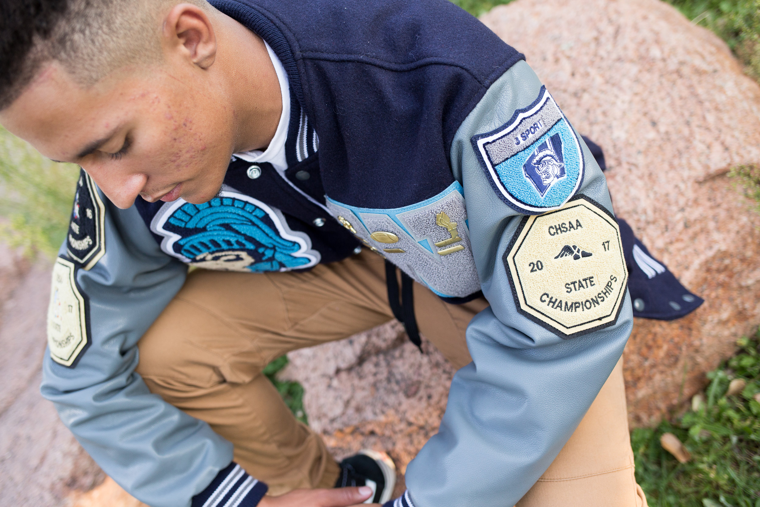 Colorado Springs senior photography in Monument Valley Park with a close up of the badges on the varsity jacket for Widefield High School Stacy Carosa Photography