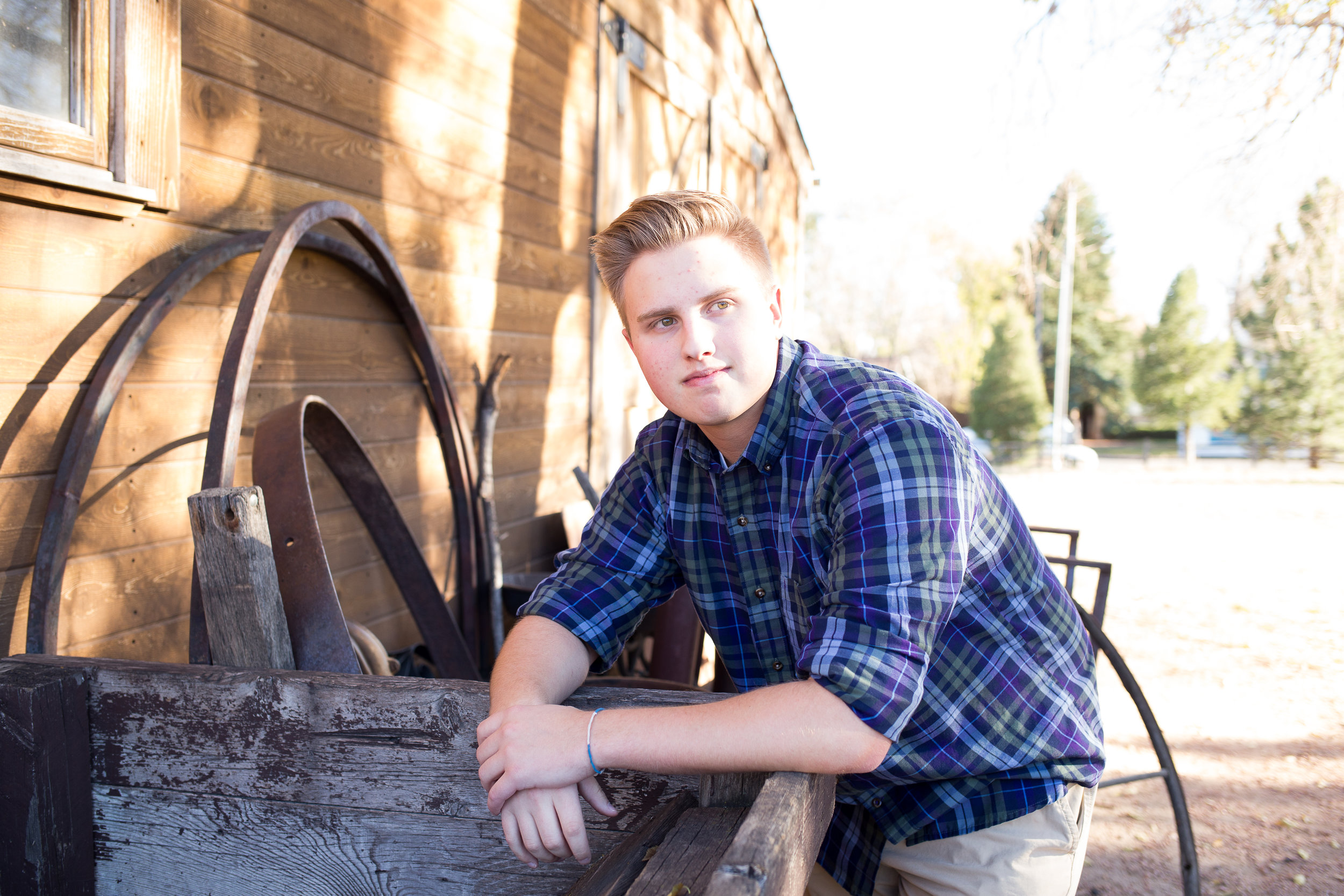 Senior session at Rock Ledge Ranch of St. Mary's boy leaning against crate and looking at camera Stacy Carosa Photography Colorado Springs