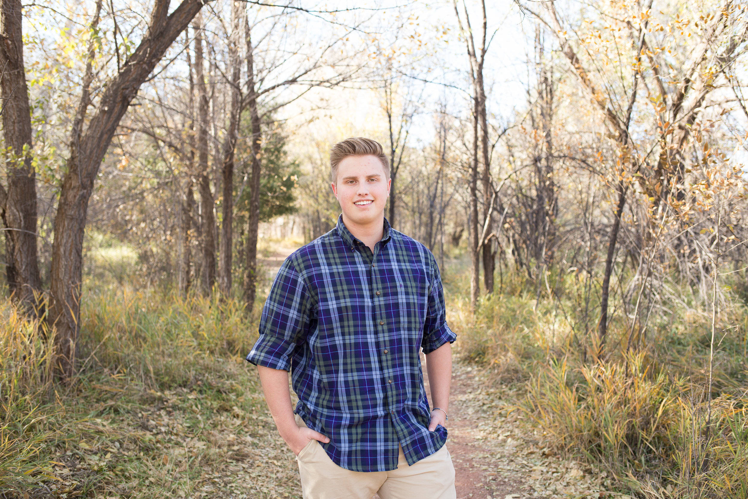 During a senior session boy standing on path among the trees at Rock Ledge Ranch Colorado Springs Stacy Carosa Photography