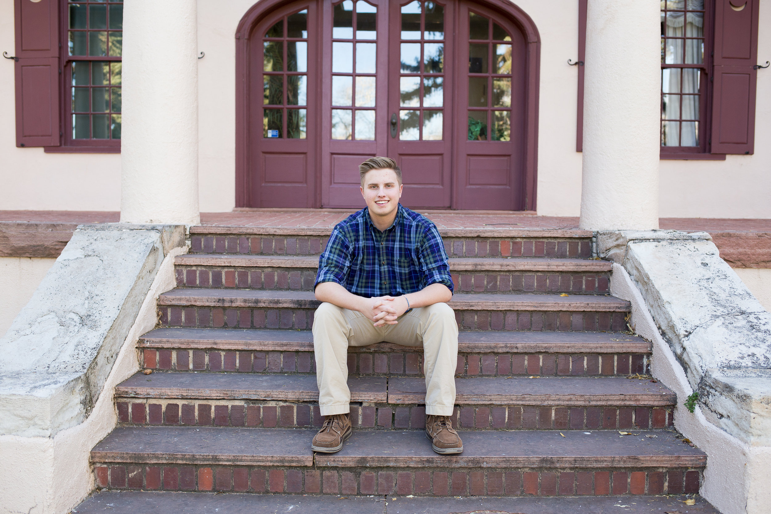 Senior session at Rock Ledge Ranch boy sitting on house steps with hands folded together Rock Ledge Ranch Stacy Carosa Photography Colorado Springs