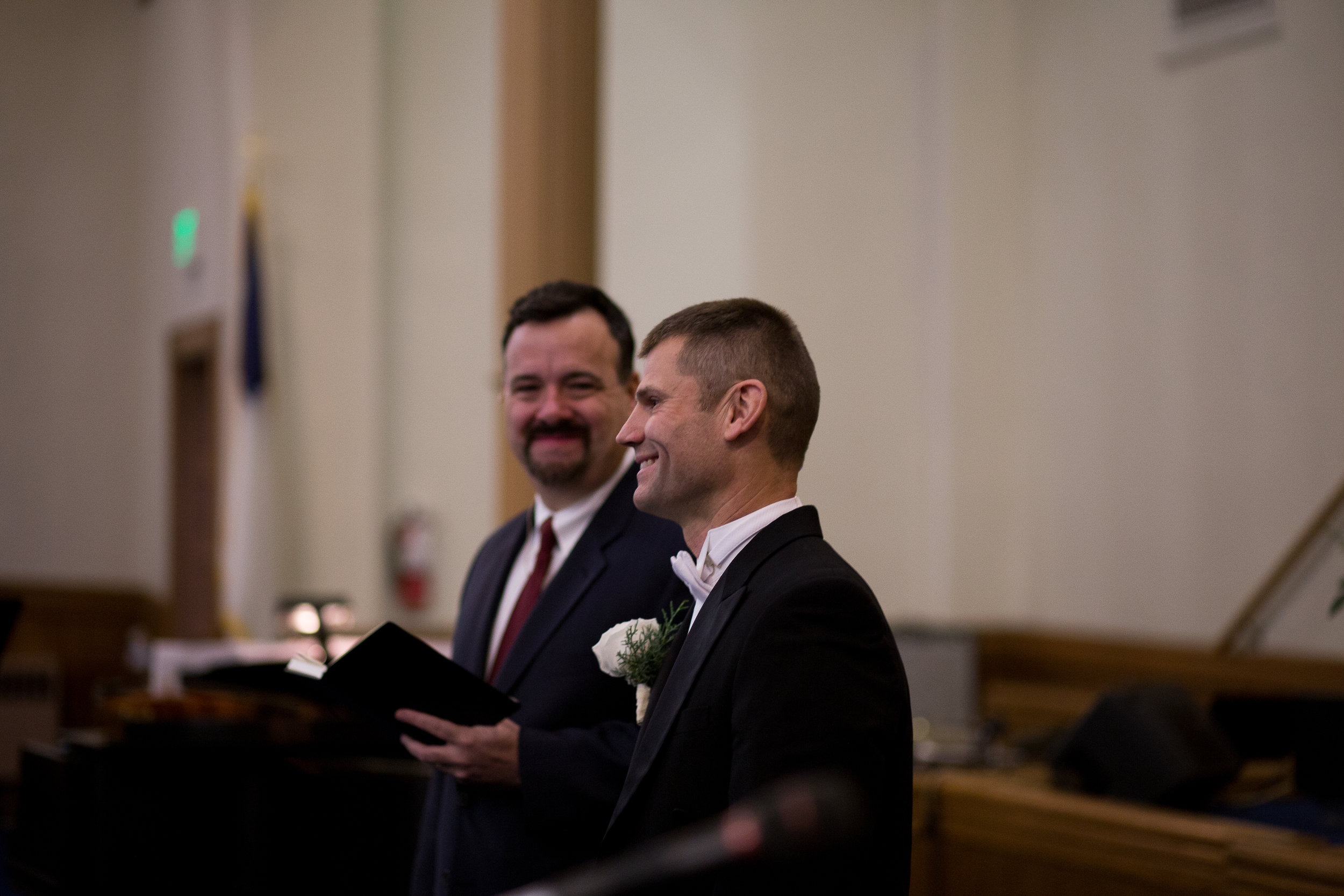 Groom smiles as a watches his bride walk down aisle at First Baptist Church wedding in Colorado Springs Stacy Carosa Photography