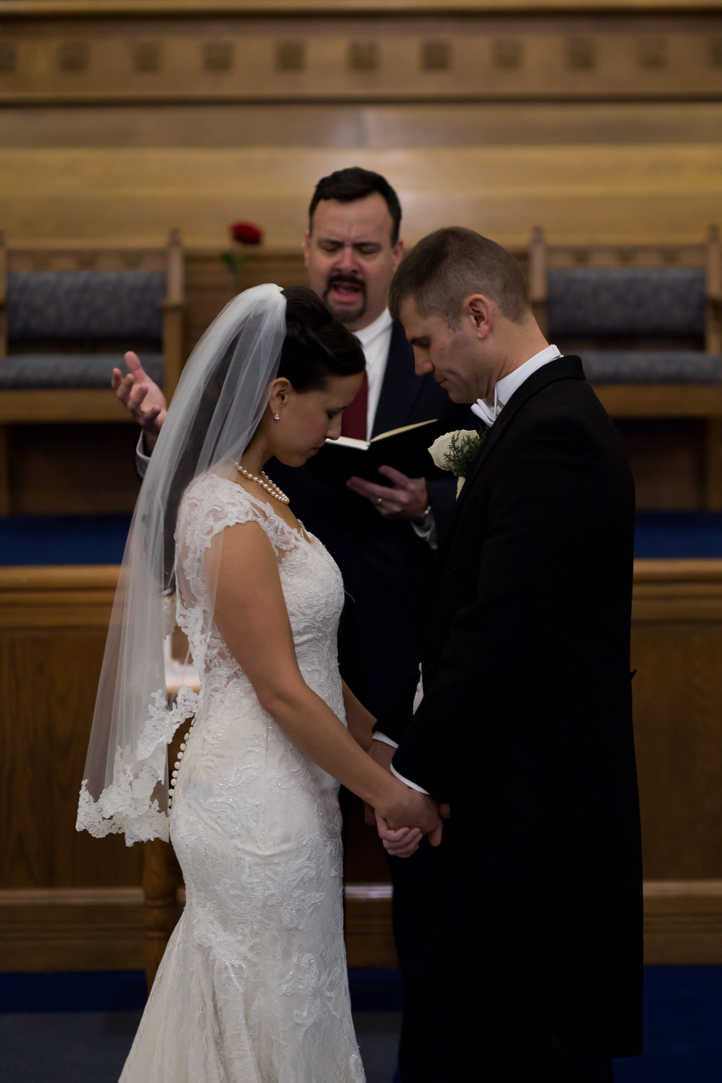 Bride and groom taking a blessing during their wedding at First Baptist Church in Colorado Springs Stacy Carosa Photography
