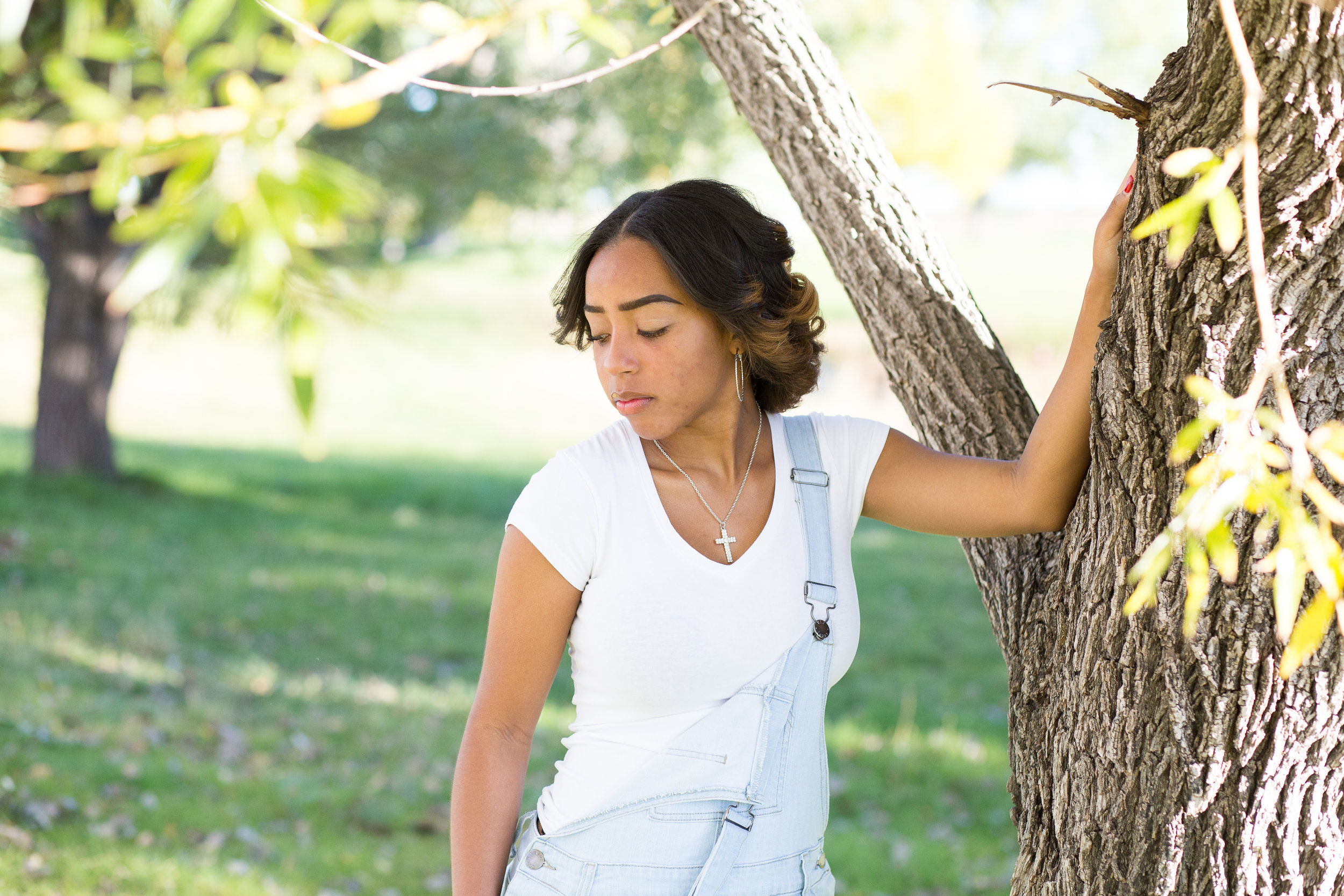 Widefield High School in Colorado Springs Senior Photographer Girl holding on to side of tree and looking at ground in deep thought Stacy Carosa Photography