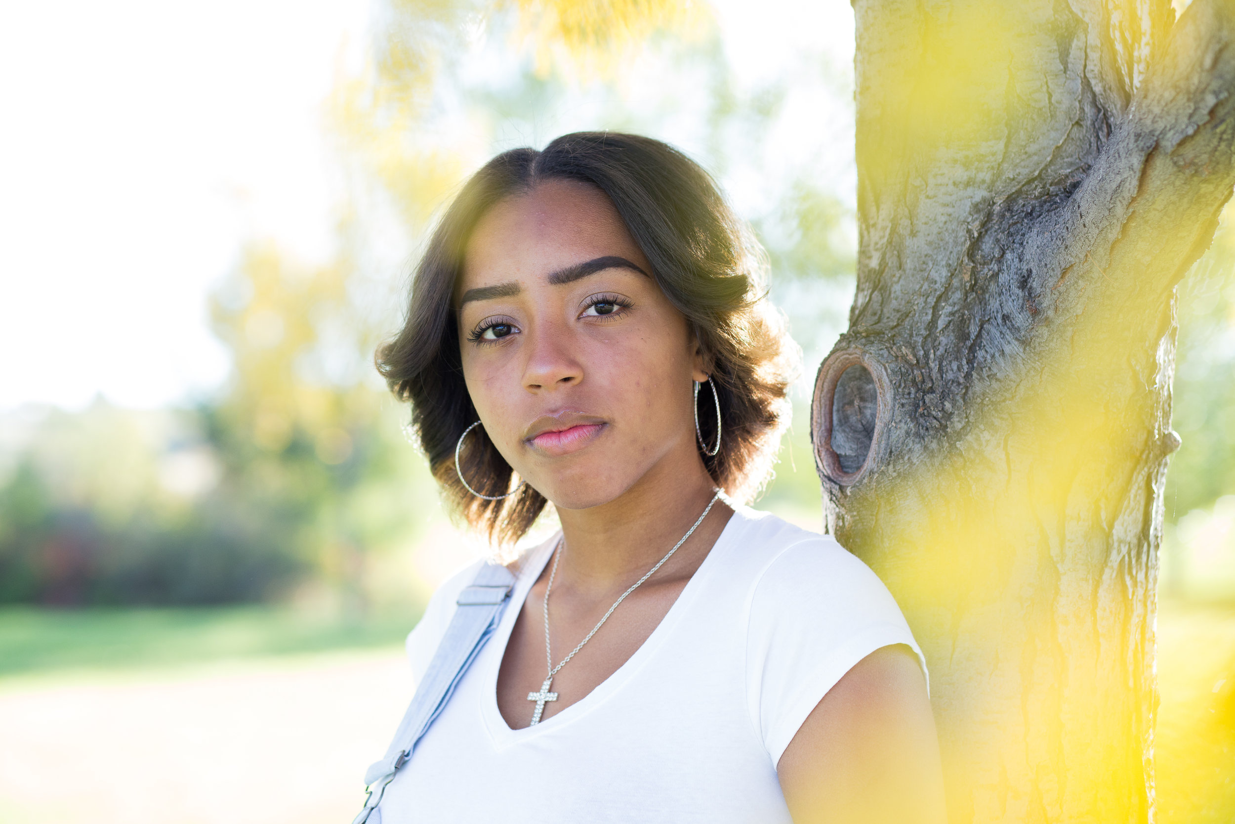 Senior girl looking seriously at the camera with yellow leaves in the foreground at Fountain Creek Regional Park Widefield High School Stacy Carosa Photography Colorado Springs Senior Photos