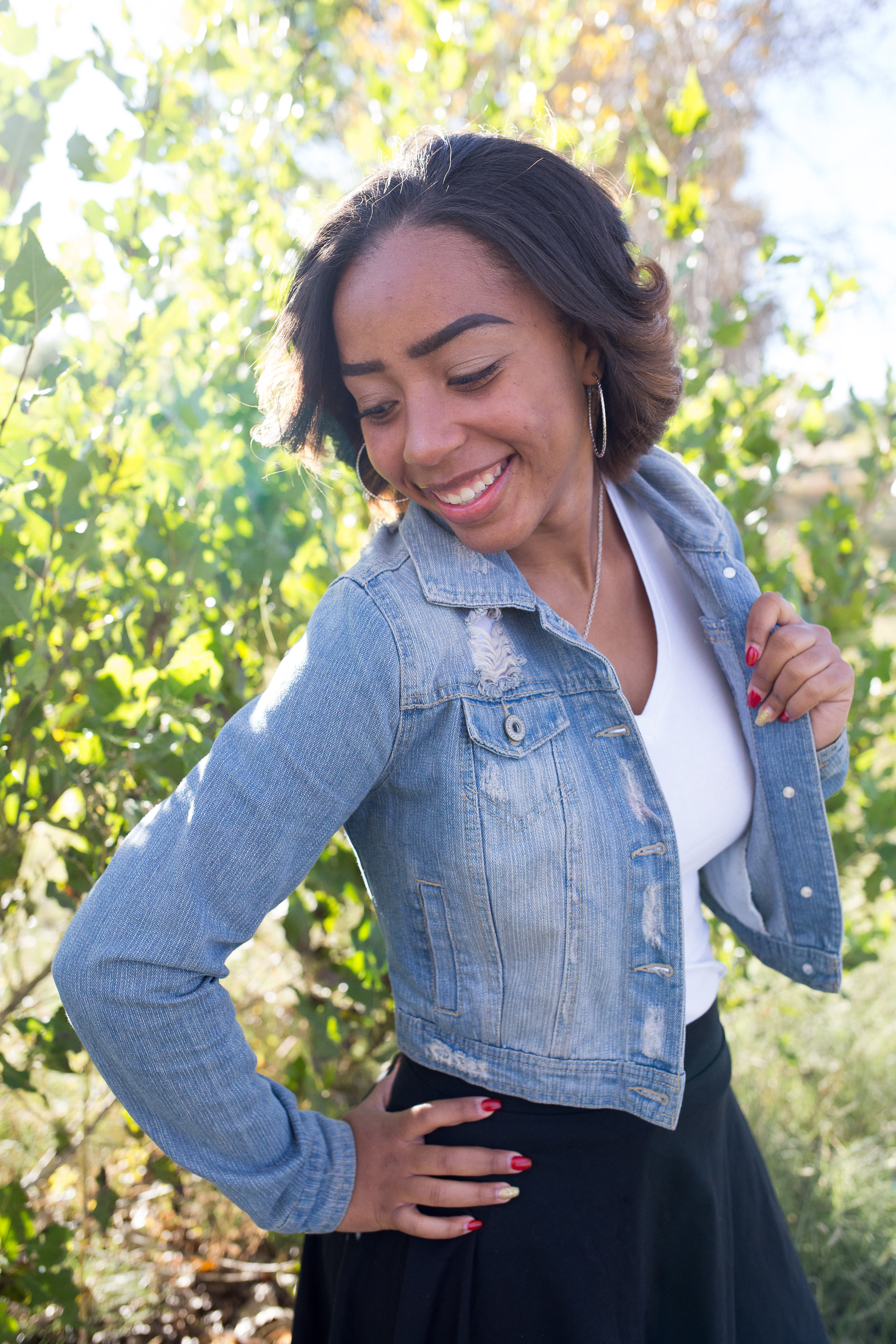 Widefield High School Senior holding jean jacket and looking over her shoulder at Fountain Creek Regional Park in Colorado Springs, CO Stacy Carosa Photography