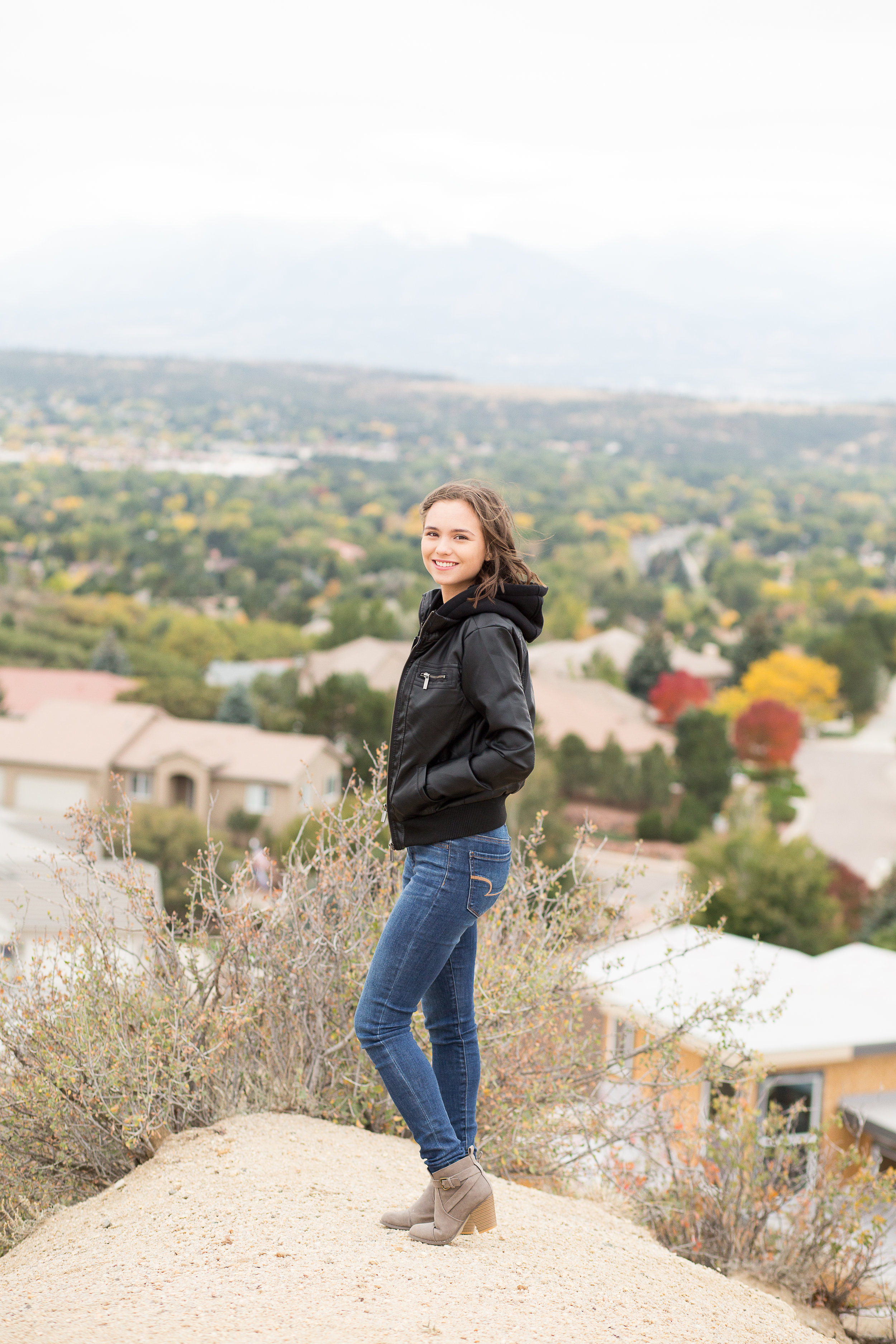 Colorado Springs Senior Photography | Doherty High School | Stacy Carosa Photography | Senior girl smiling at camera with mountain backdrop on a windy day