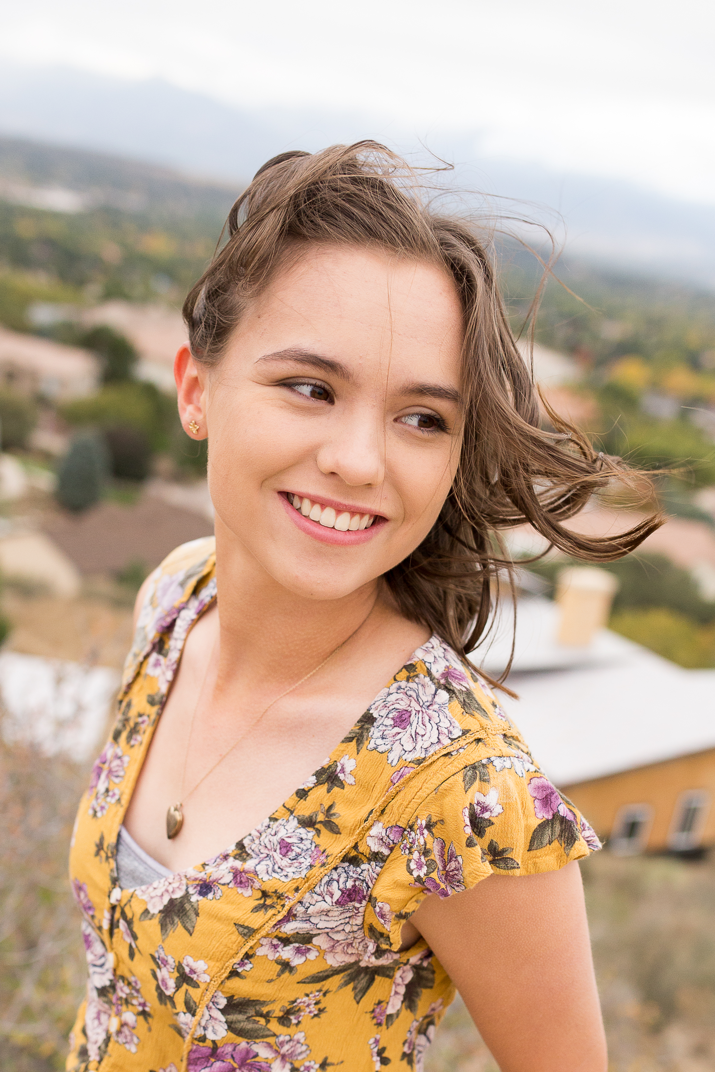 Colorado Springs Senior Photography | Doherty High School | Stacy Carosa Photography | Senior girl smiling at camera with mountain backdrop on a windy day