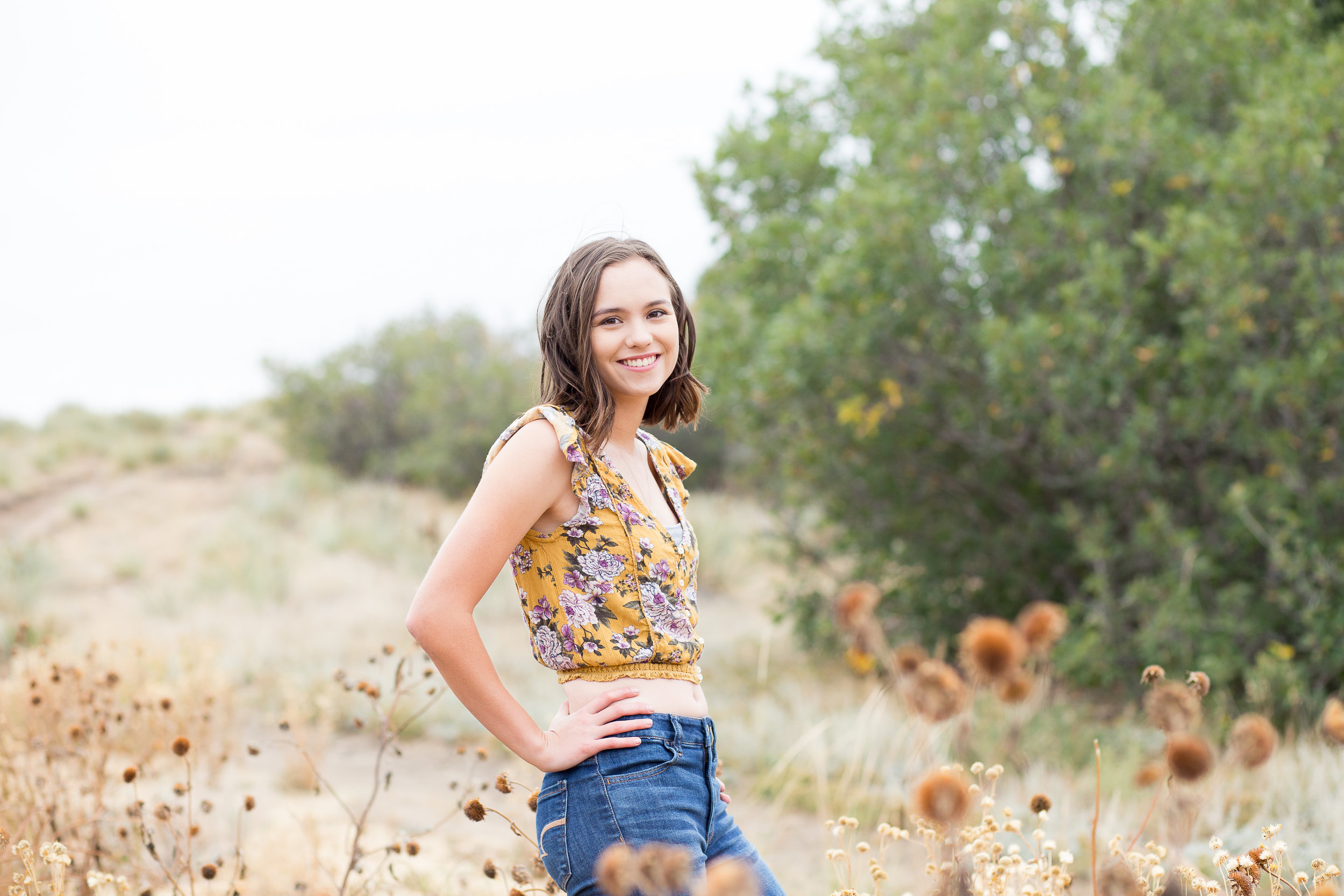 Colorado Springs Senior Photography | Doherty High School | Stacy Carosa Photography | Senior girl smiling at camera surrounded by tall grasses in the fall