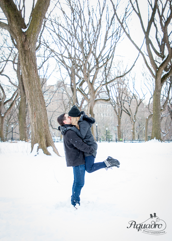 engaged couple embrace and kiss in snowy Central Park