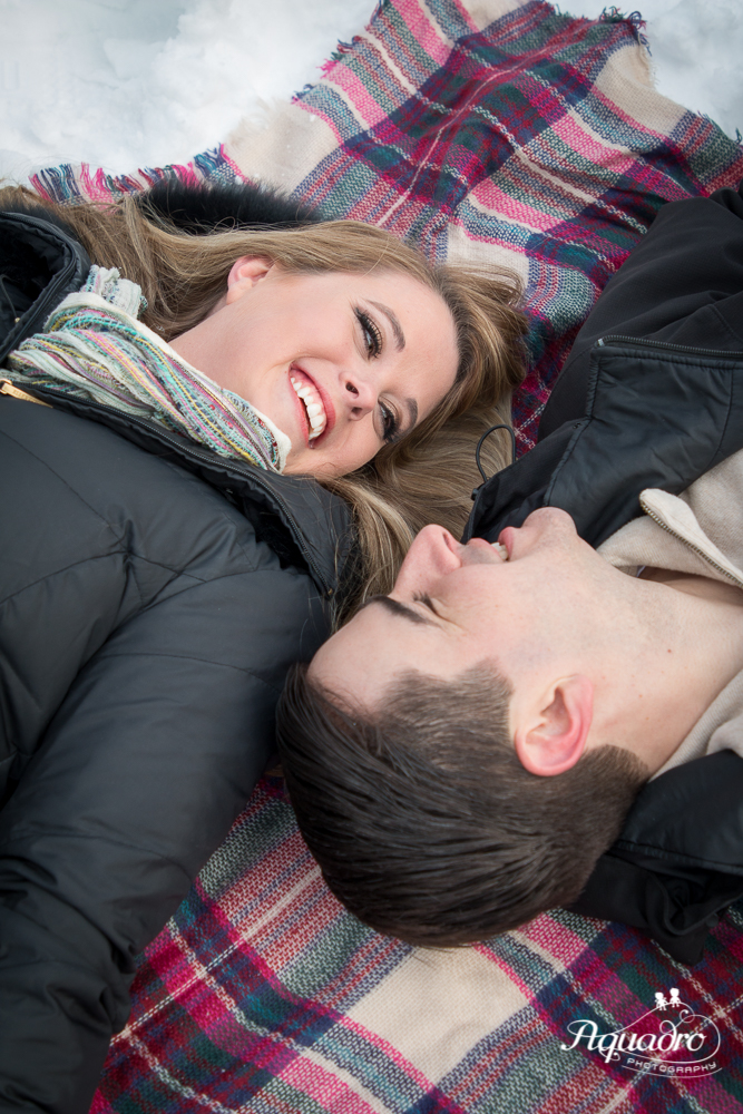 engaged couple laying on a blanket in Snowy Central Park