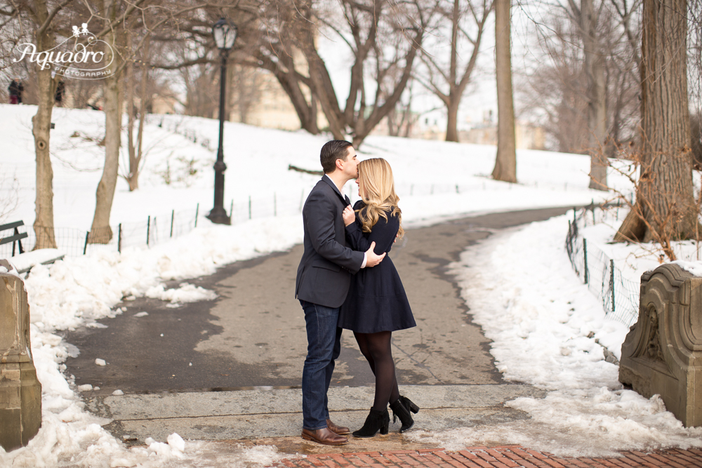 engaged couple share an intimate embrace in snowy Central Park
