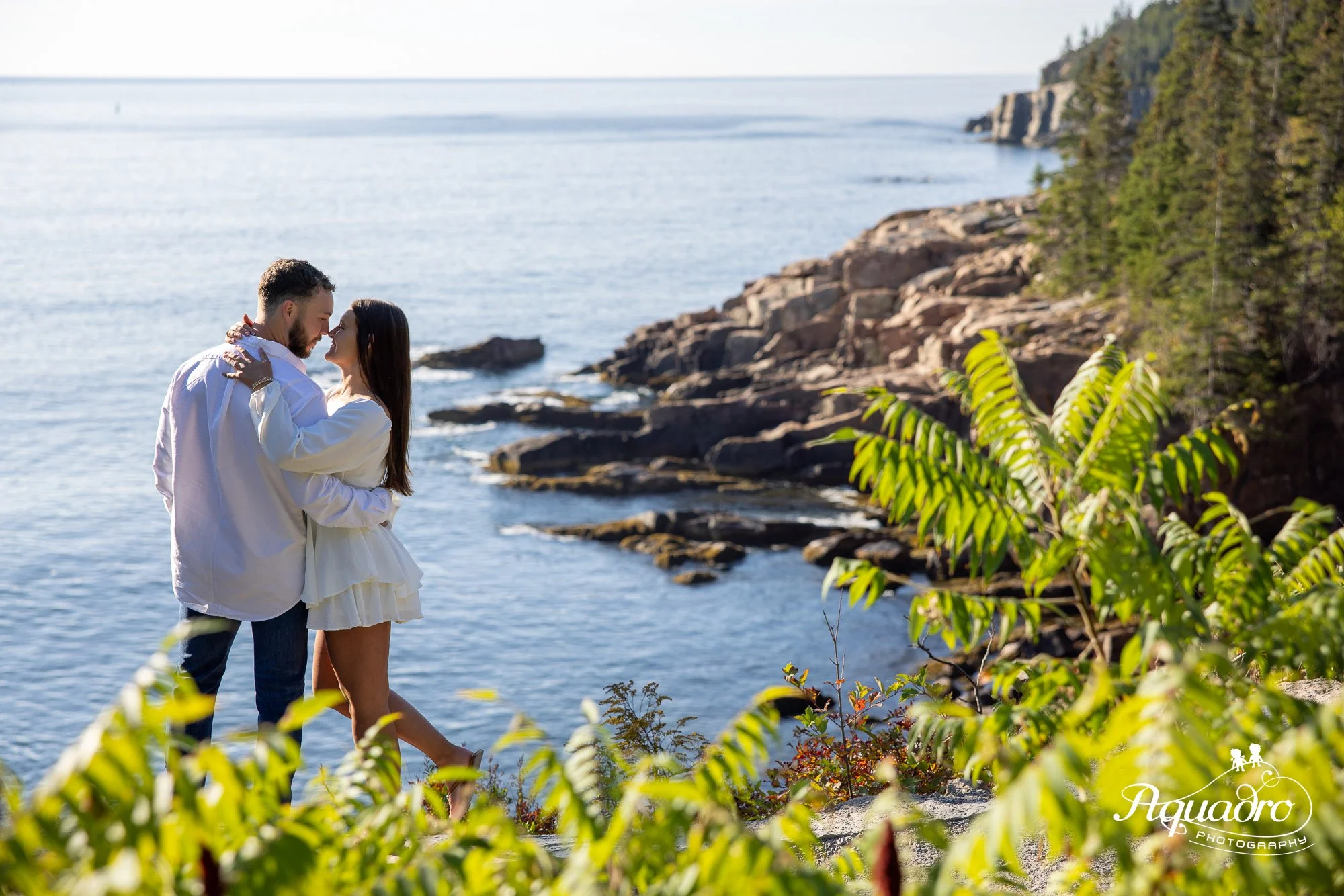 couple celebrates engagement on ocean path in summer in acadia on ocean path near bar harbor