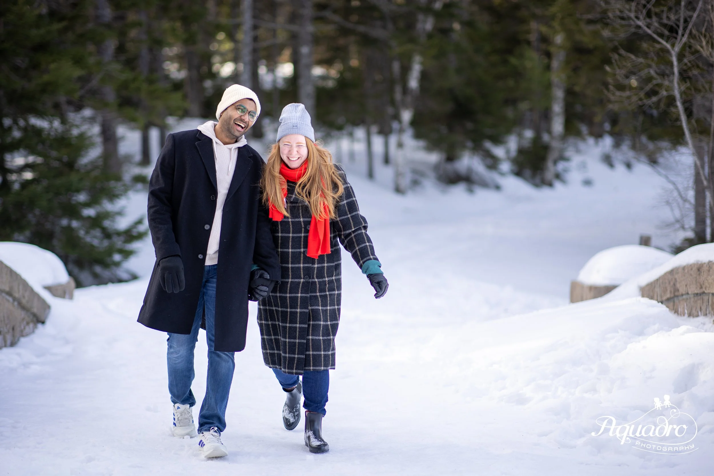 winter on snowy carriage road in acadia national park near jordan pond.  couple celebrates their engagement with a photo session