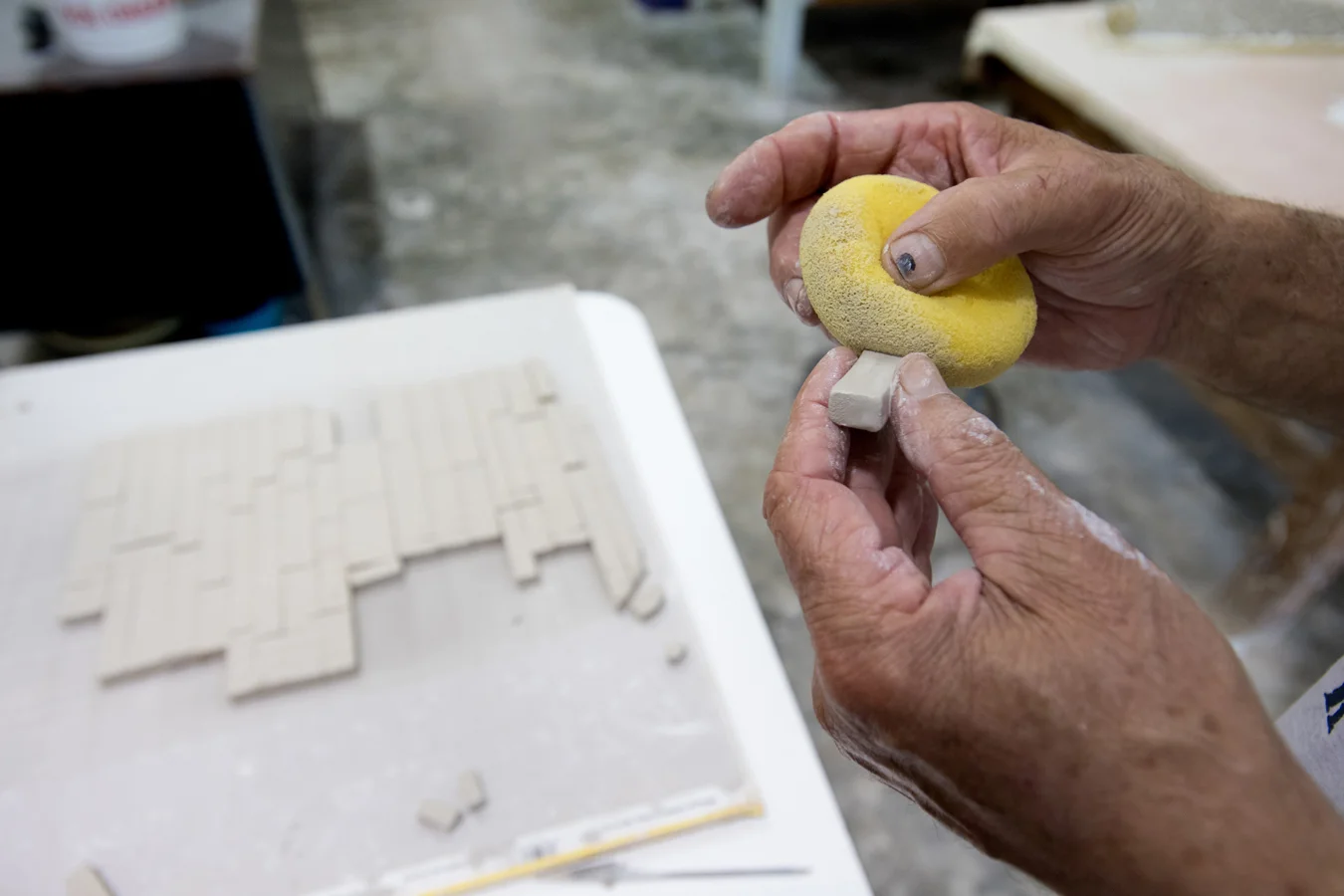 Unfired tiles being sponged prior to firing to soften and round the edges.  Photo by Michael Spooneybarger