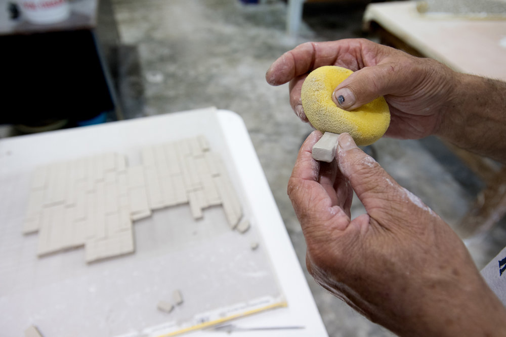  Unfired tiles being sponged prior to firing to soften and round the edges.  Photo by Michael Spooneybarger 