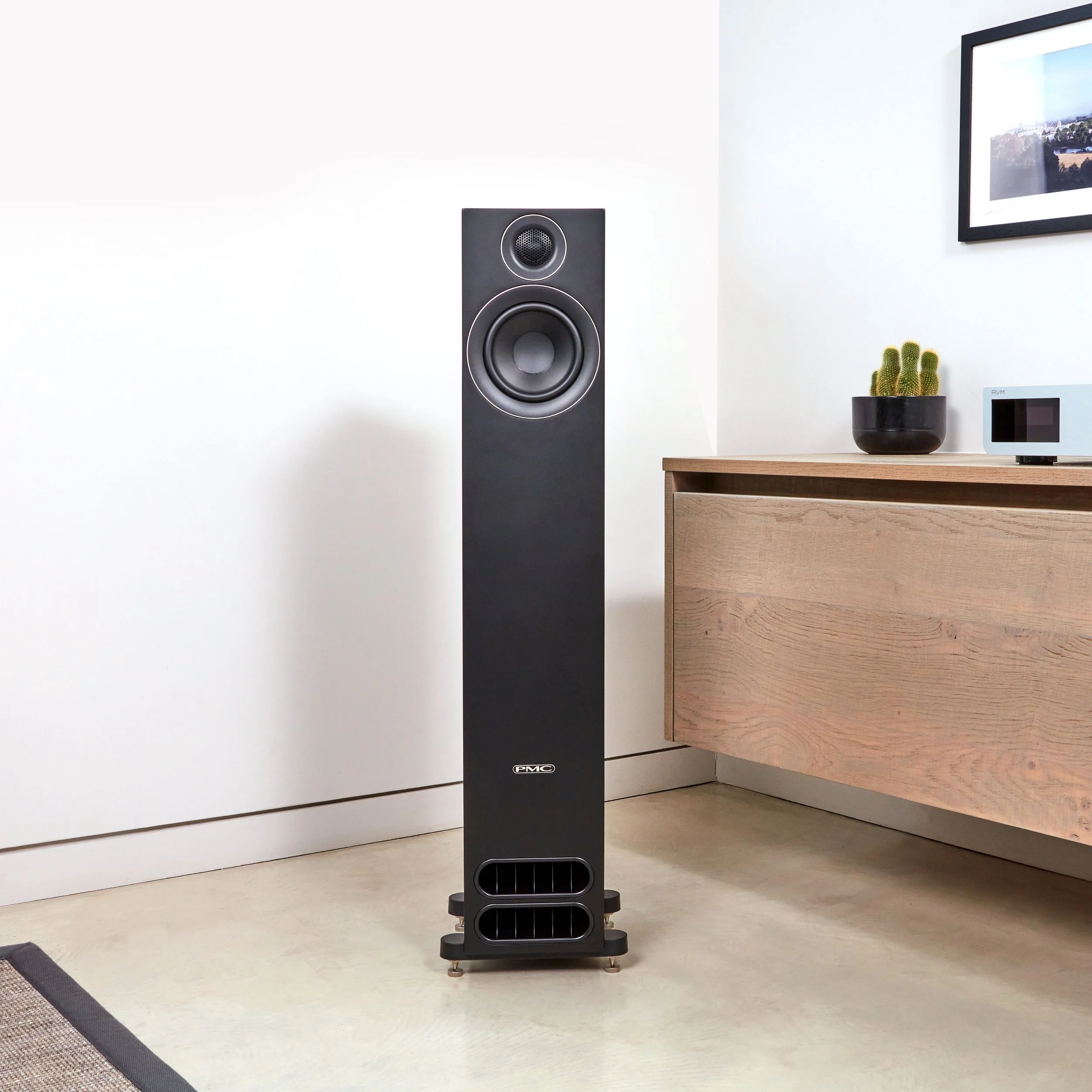 A PMC prodigy5 floorstanding speaker shown next to an oak cabinet.