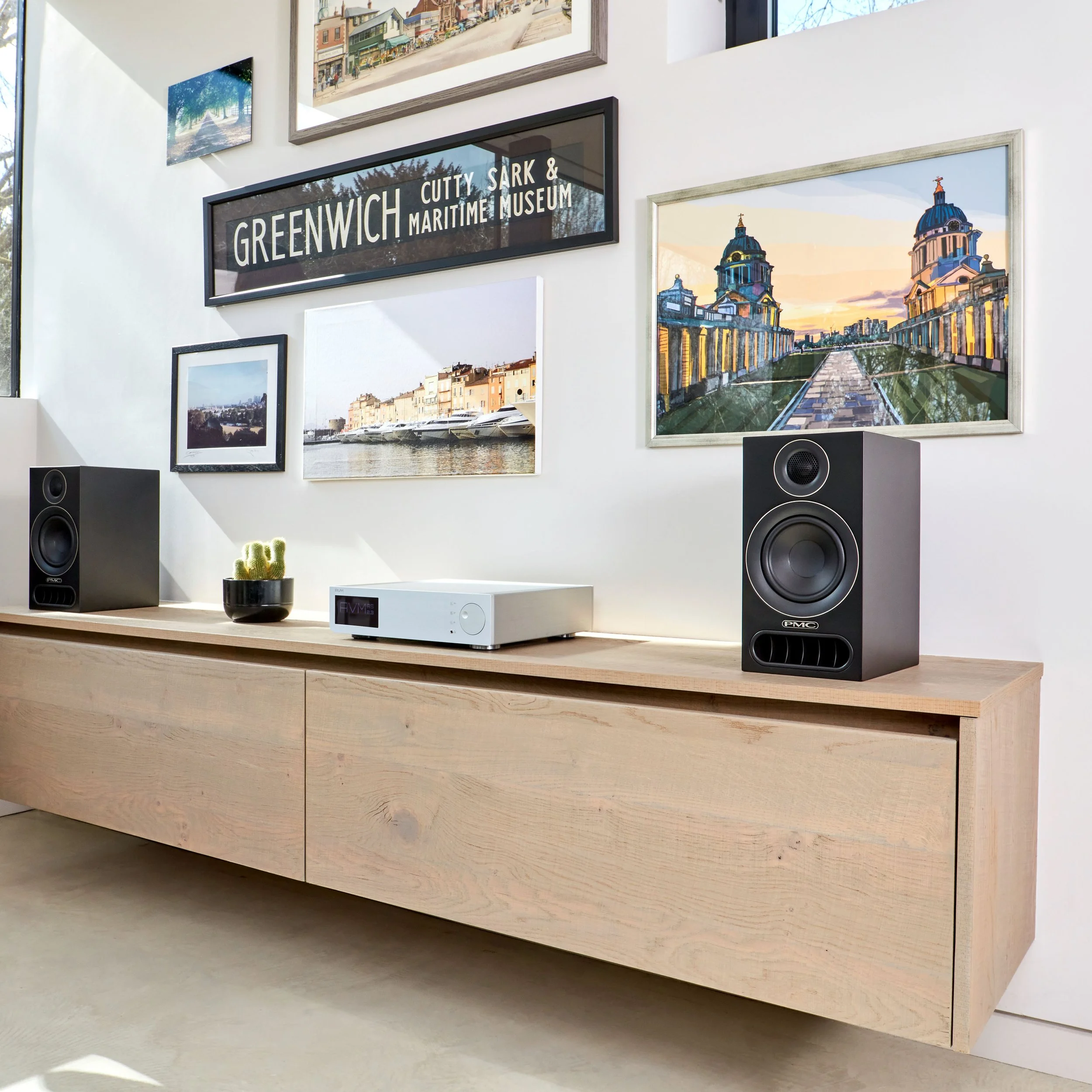 A pair of PMC prodigy1 bookshelf speakers shown on an oak cabinet.