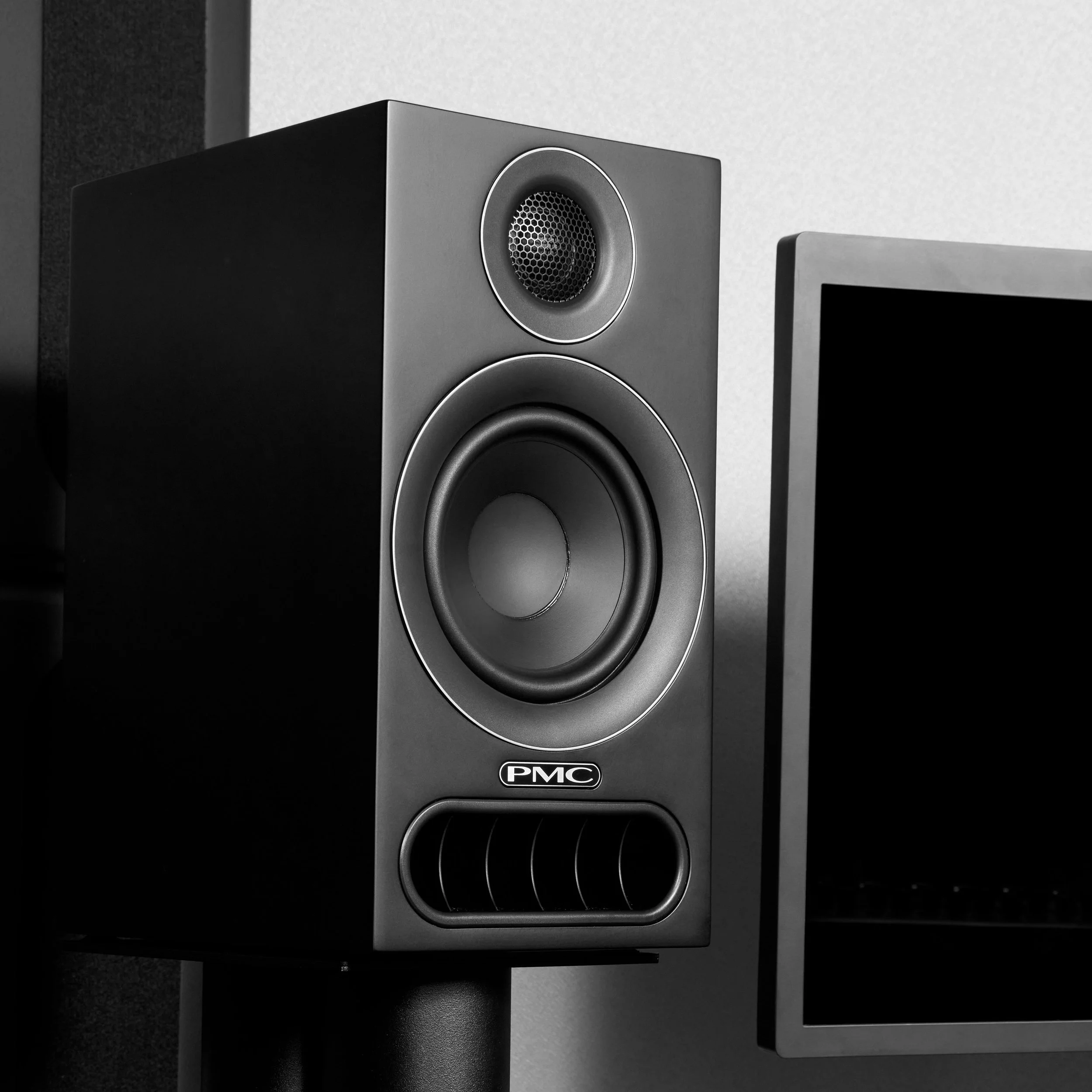 A PMC prodigy1 bookshelf speaker shown next to a computer monitor.
