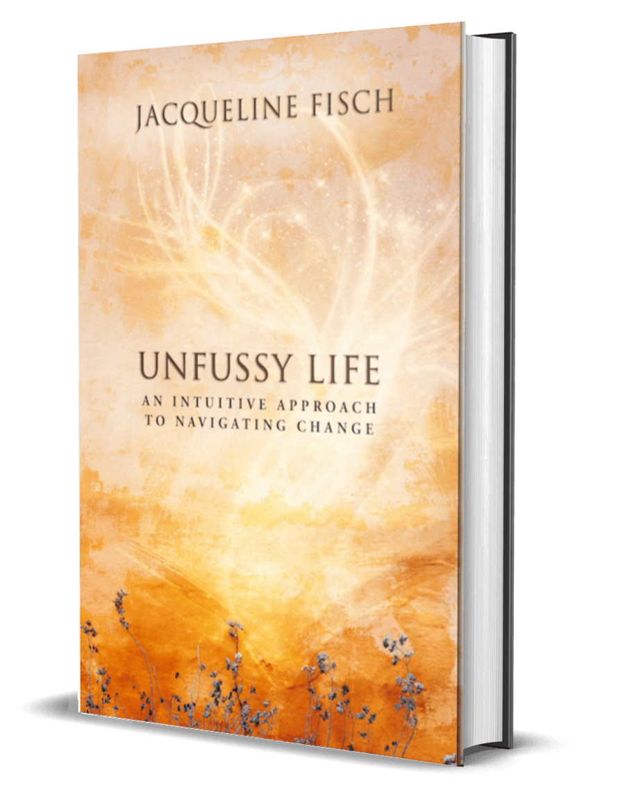 Book cover titled 'Unfussy Life: An Intuitive Approach to Navigating Change' by Jacqueline Fisch, featuring a soft orange and beige background with abstract light patterns and small flower illustrations at the bottom.