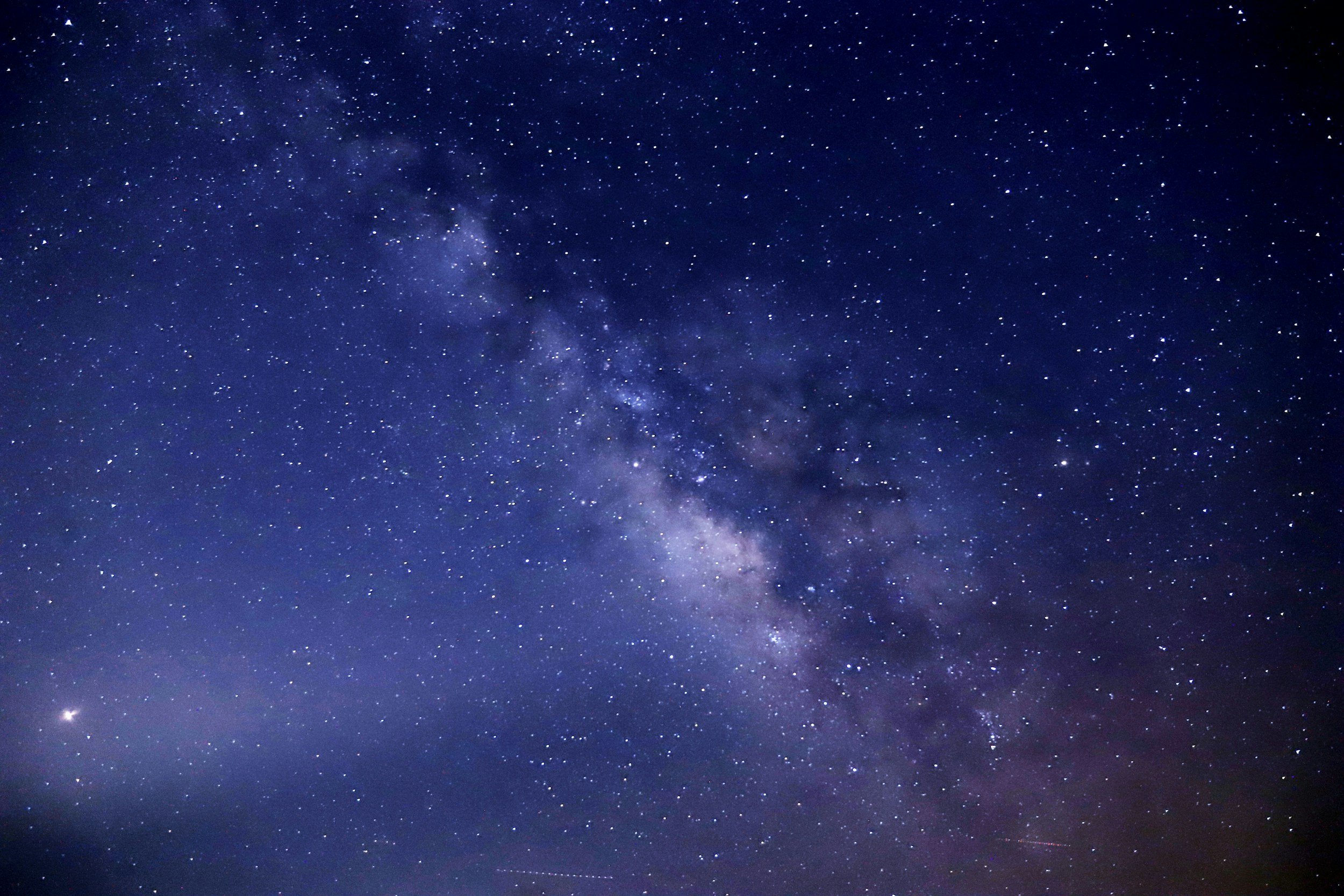 milky way in a black and purple sky illuminated by stars