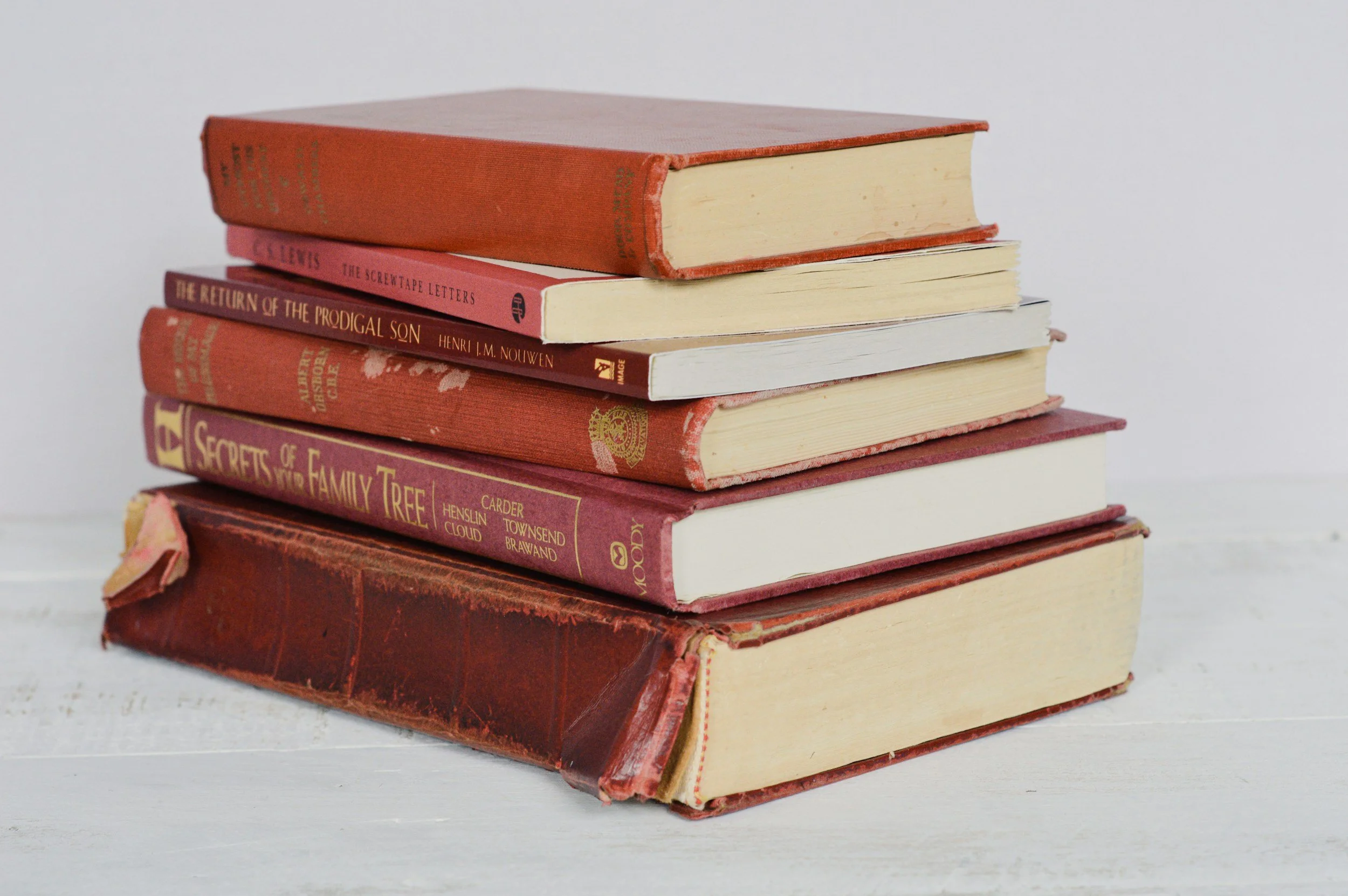 Stack of ancient nonfiction and memoir books with a red spine