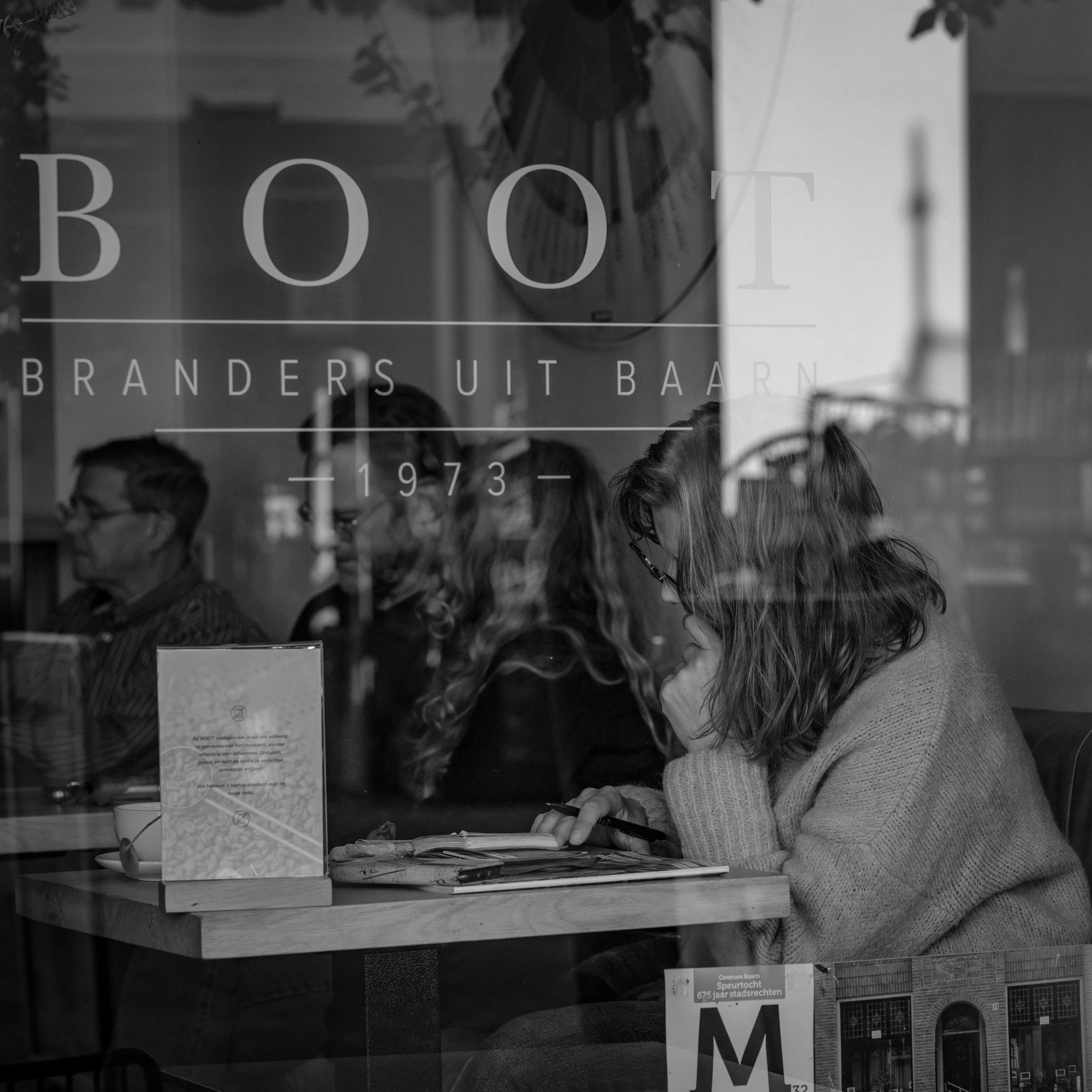 black and white photo of a women inside a bookstore writnig
