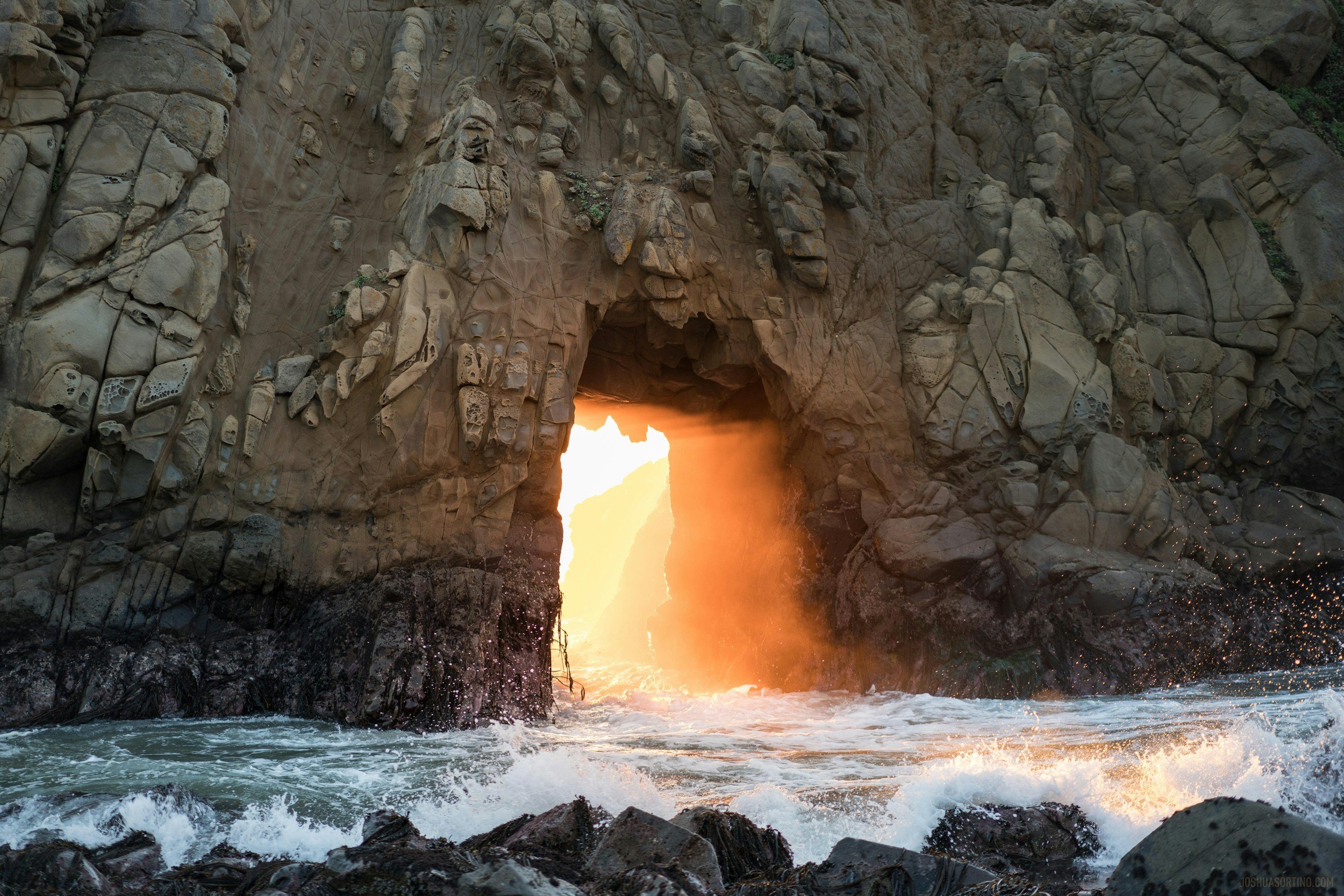 stone structure over the ocean with golden sunlight radiating through a doorway