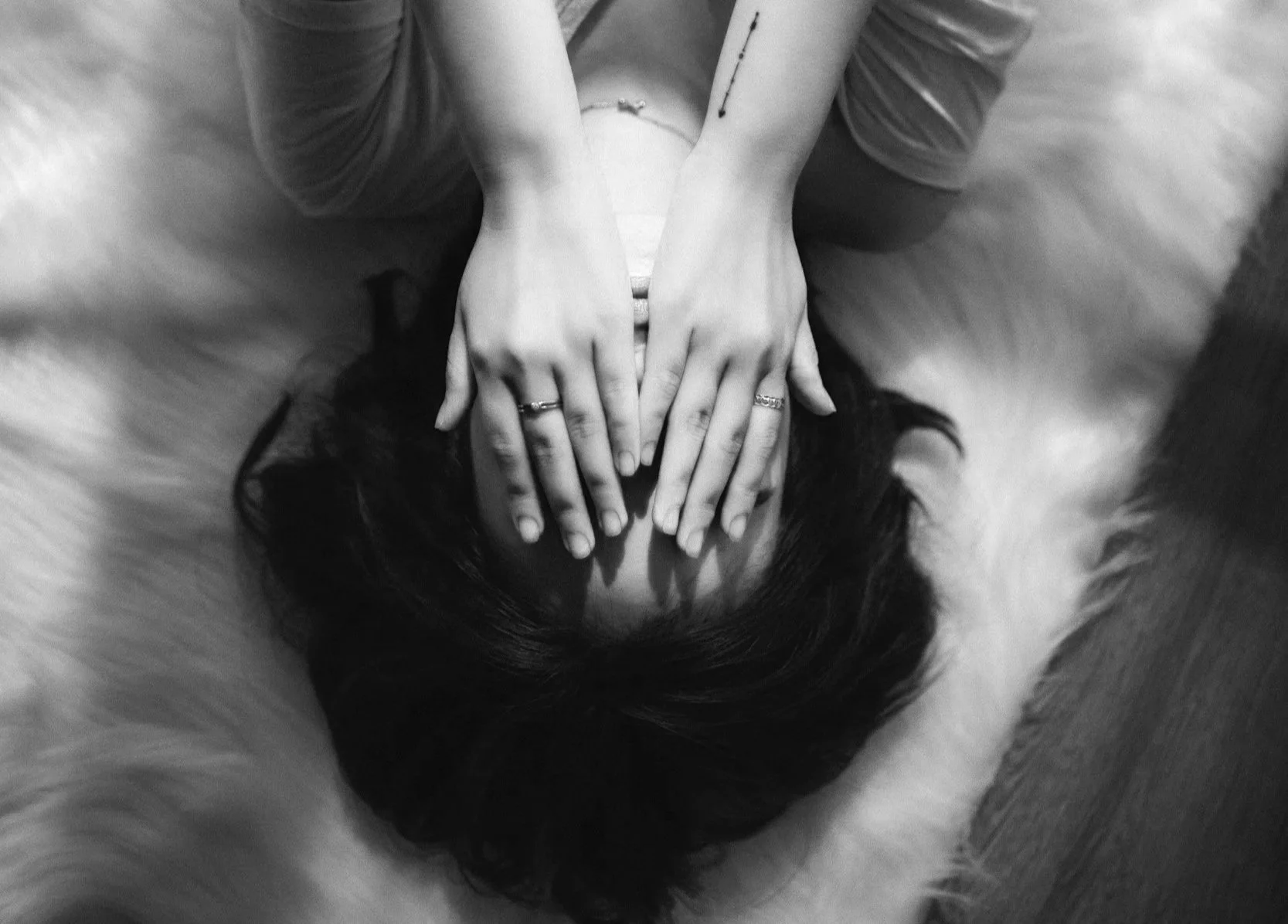 black and white image of a woman with her hands over her face, laying down