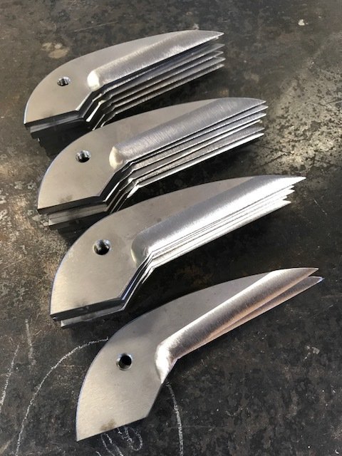 four rows of shear blades stacked several blades high and laying flat on a metal table.JPG