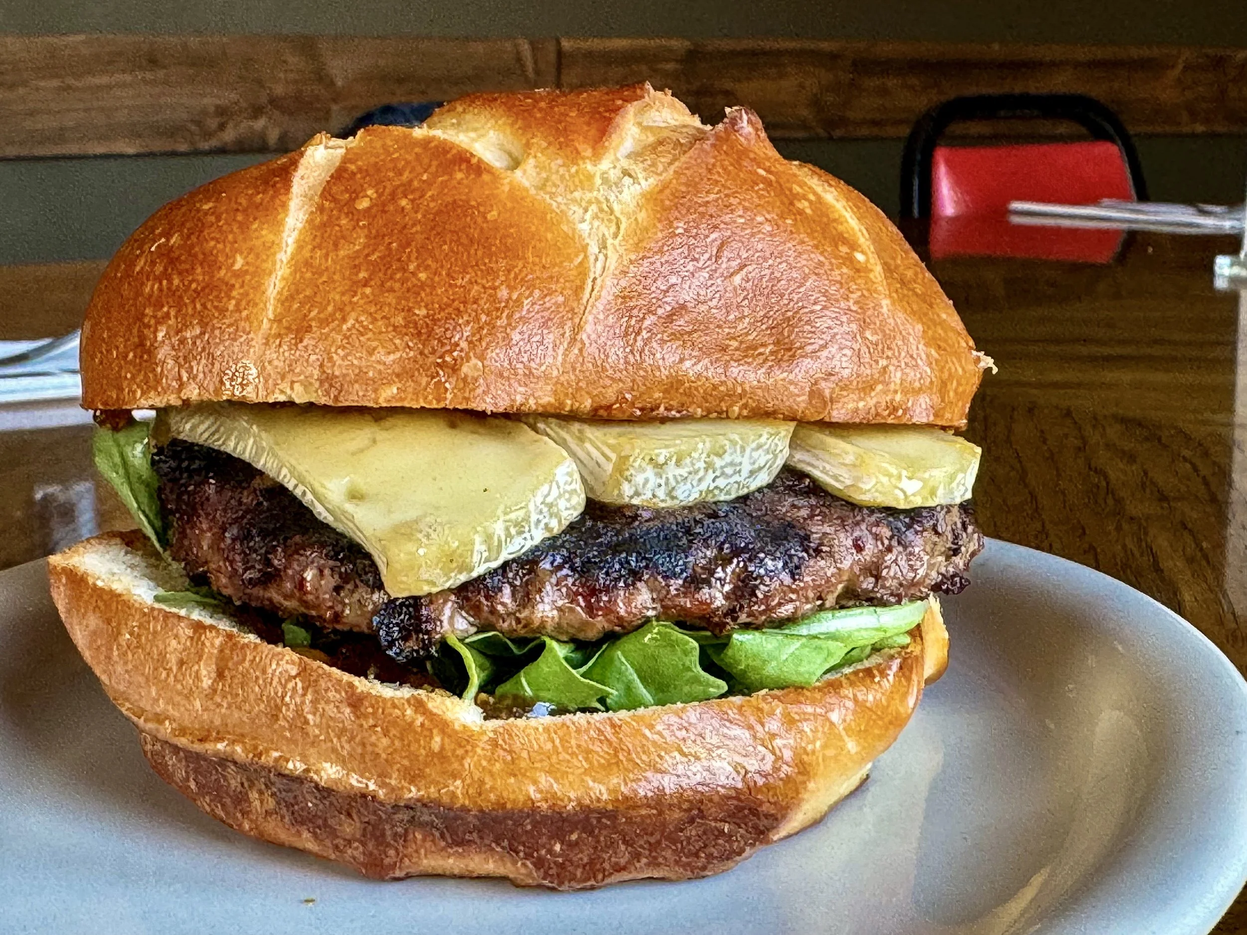 A cheeseburger with lettuce and pickles on a plate.