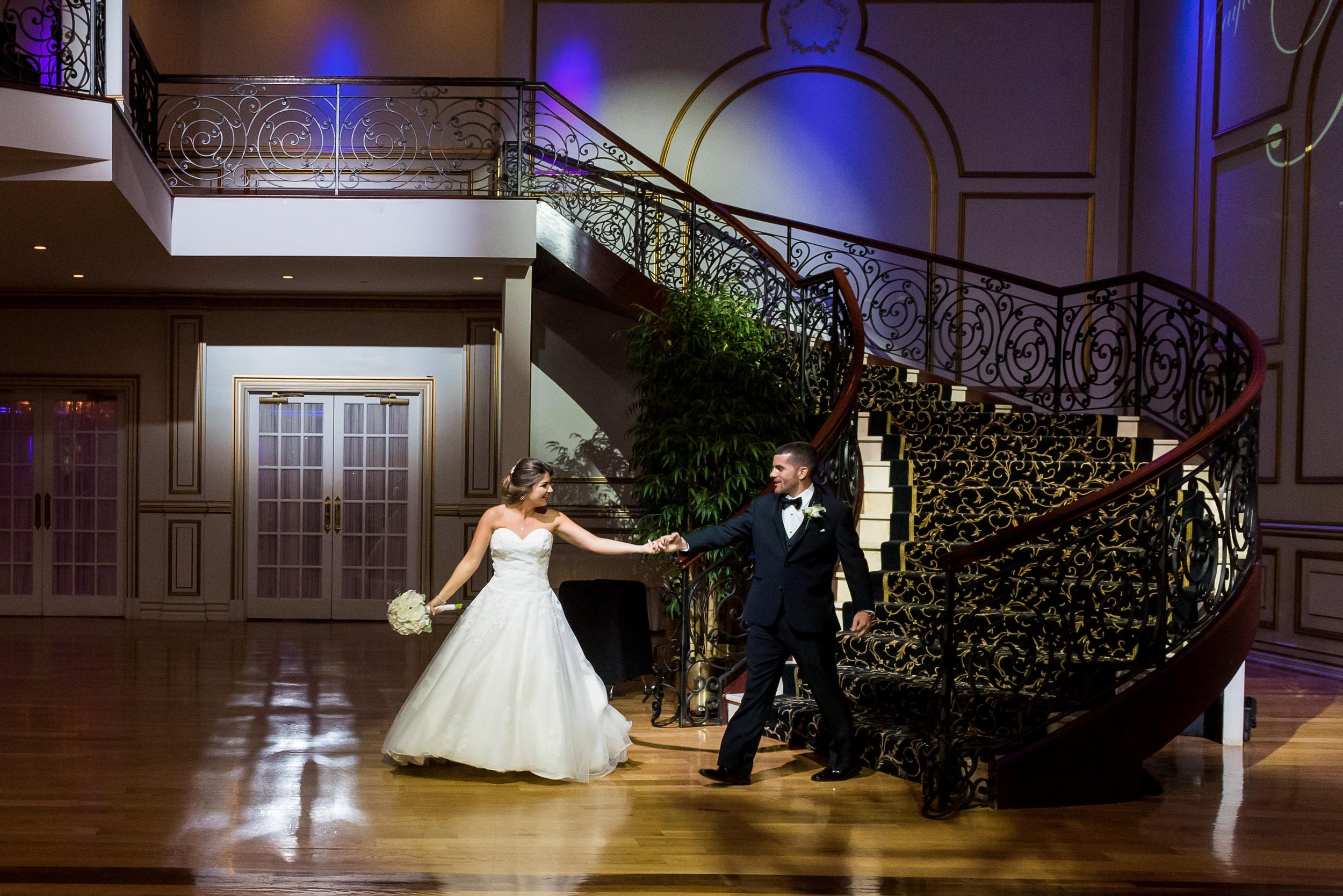 Bride and groom dancing beneath the grand staircase inside The Tides wedding venue in New Jersey
