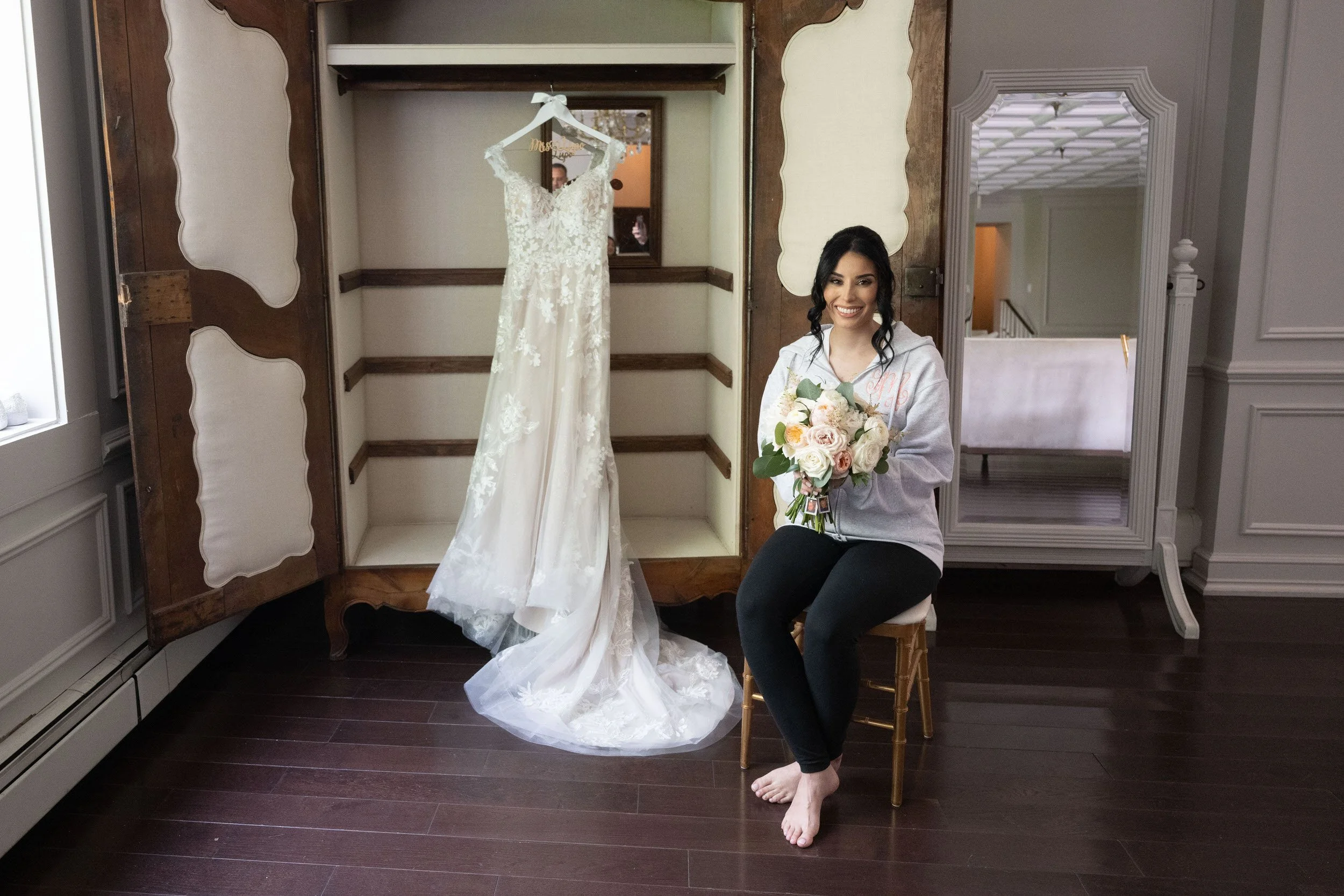 Bride sitting beside wedding dress on hanger at Valley Regency bridal suite