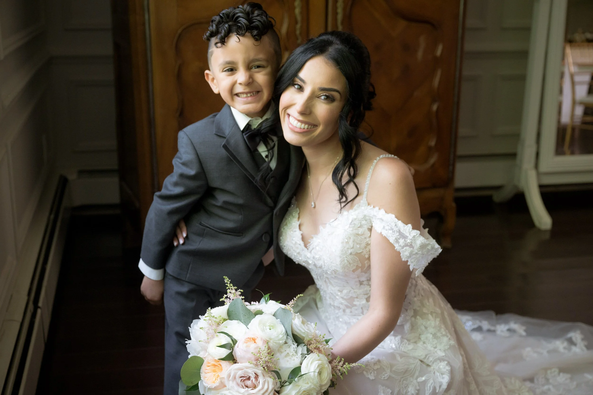 Bride with young ring bearer smiling before Valley Regency wedding ceremony