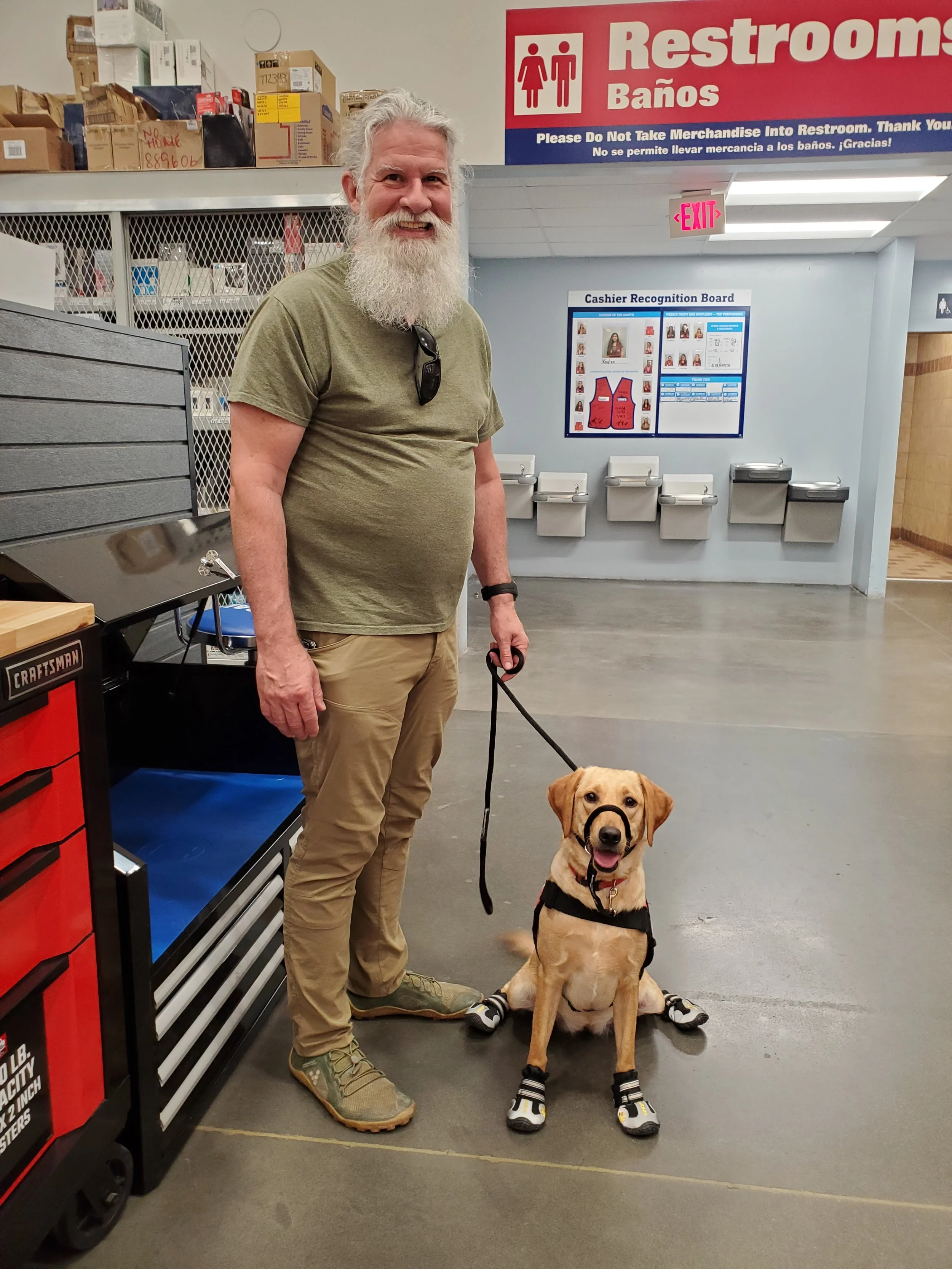 Man standing in the store with his yellow Labrador PSD service dog.