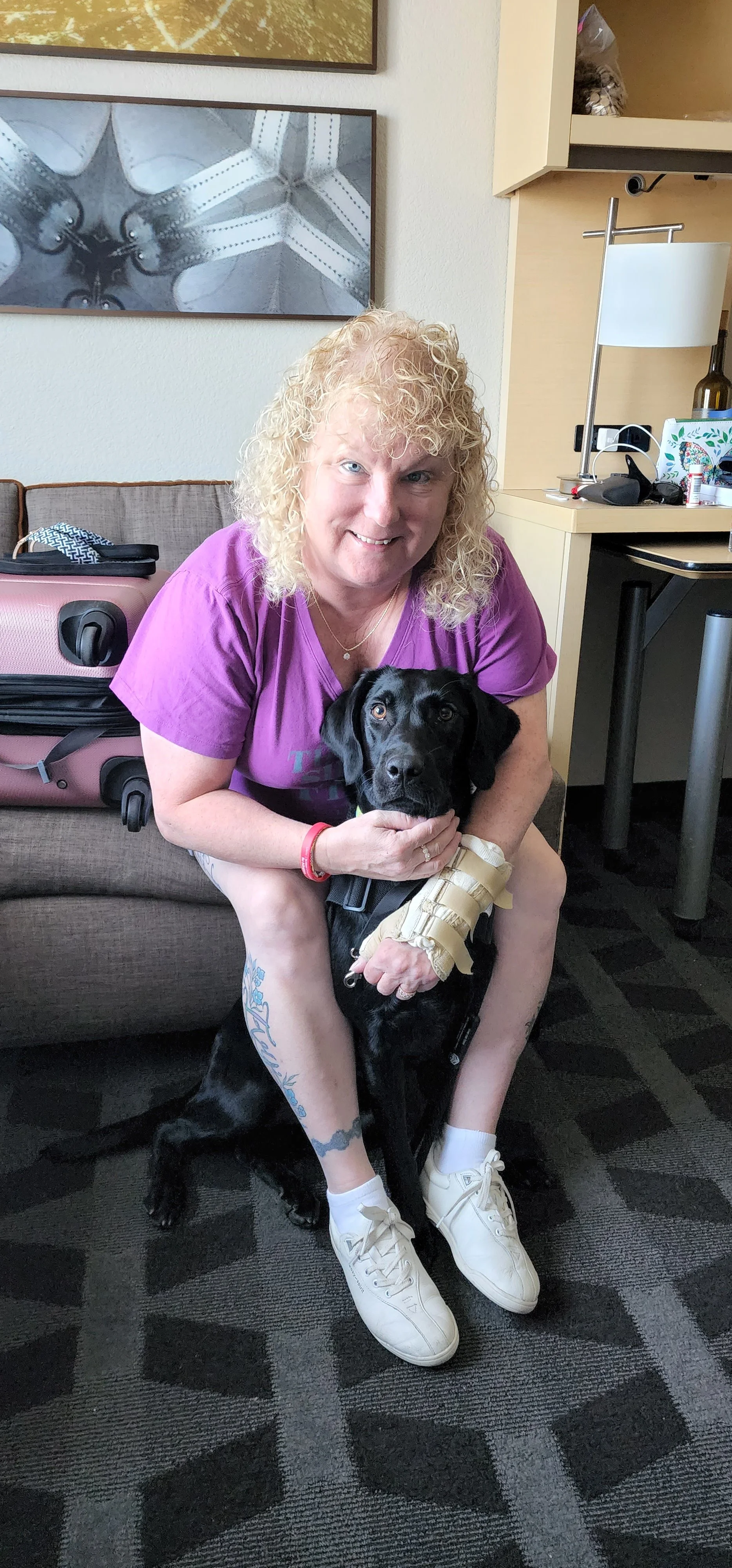 Woman sitting at home with her small black psychiatric service dog