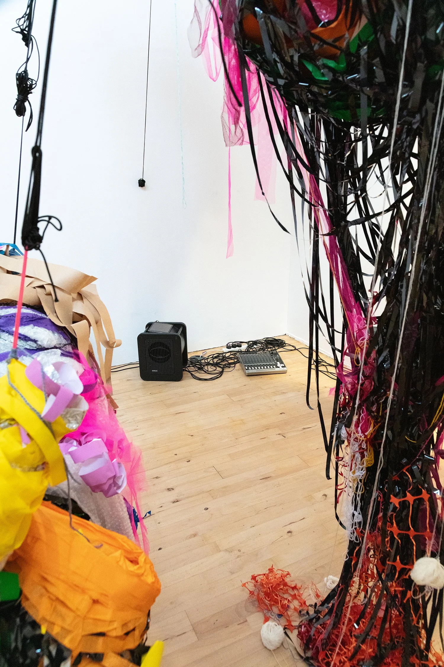 Close-up of layered materials including yellow, pink, brown, and translucent fabrics, wrapped tightly around a sculptural form.